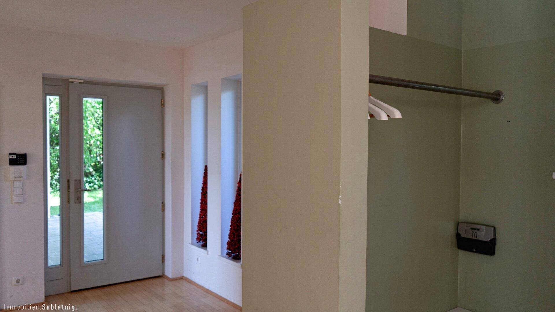 Heller Eingangsbereich mit moderner Haustür und Nische für Garderobe.