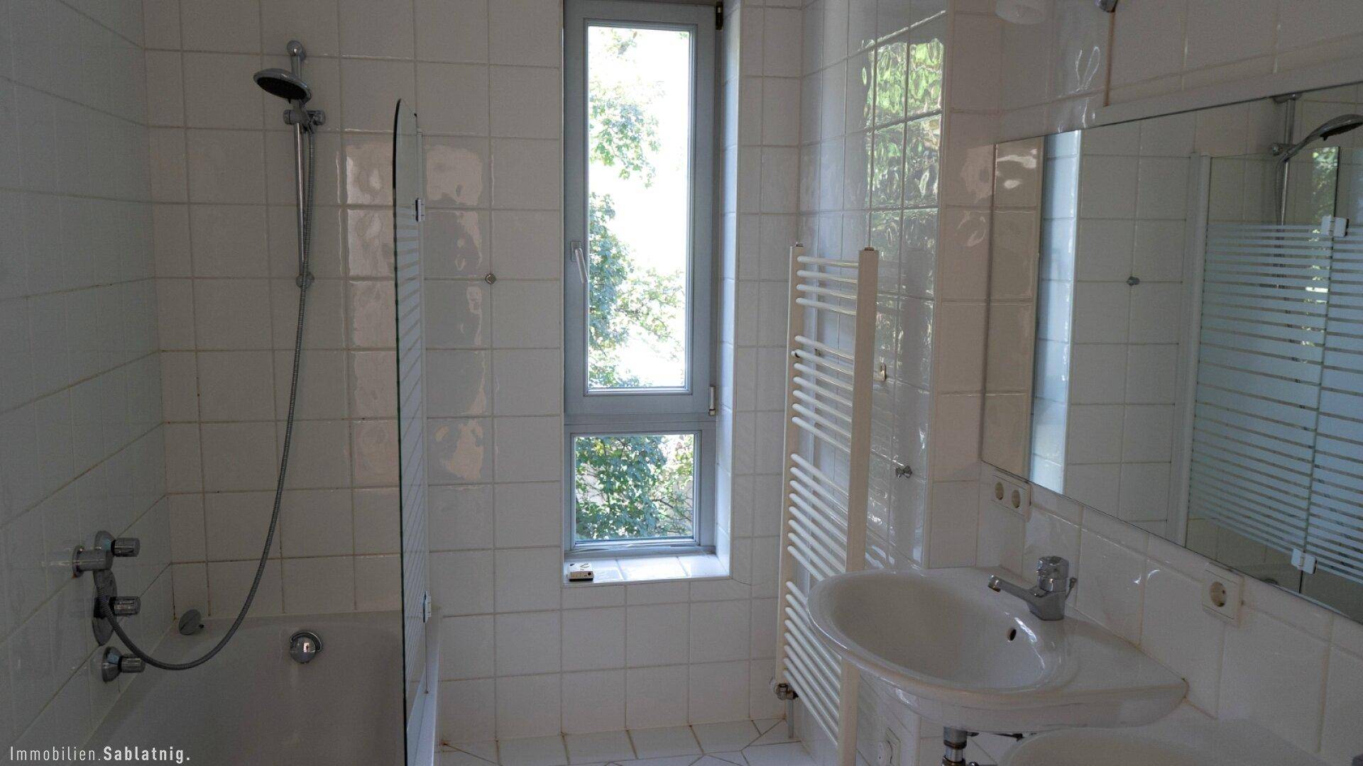 Helles Badezimmer mit Dusche, Waschbecken, Spiegelschrank, Handtuchheizkörper und Fenster.