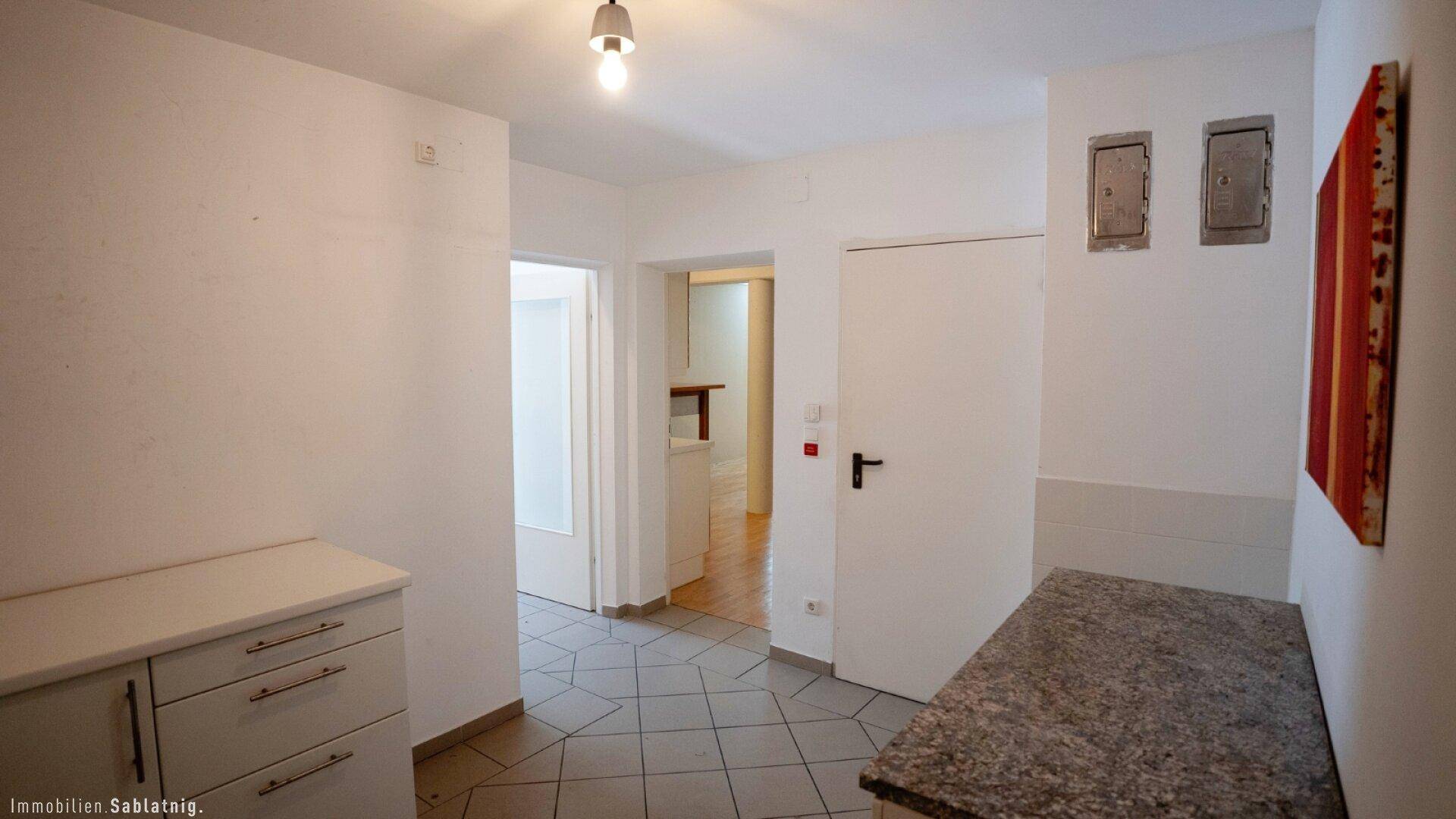 Heller Flur mit Fliesenboden, einem kleinen Schrank und Zugang zu verschiedenen Räumen der Wohnung.