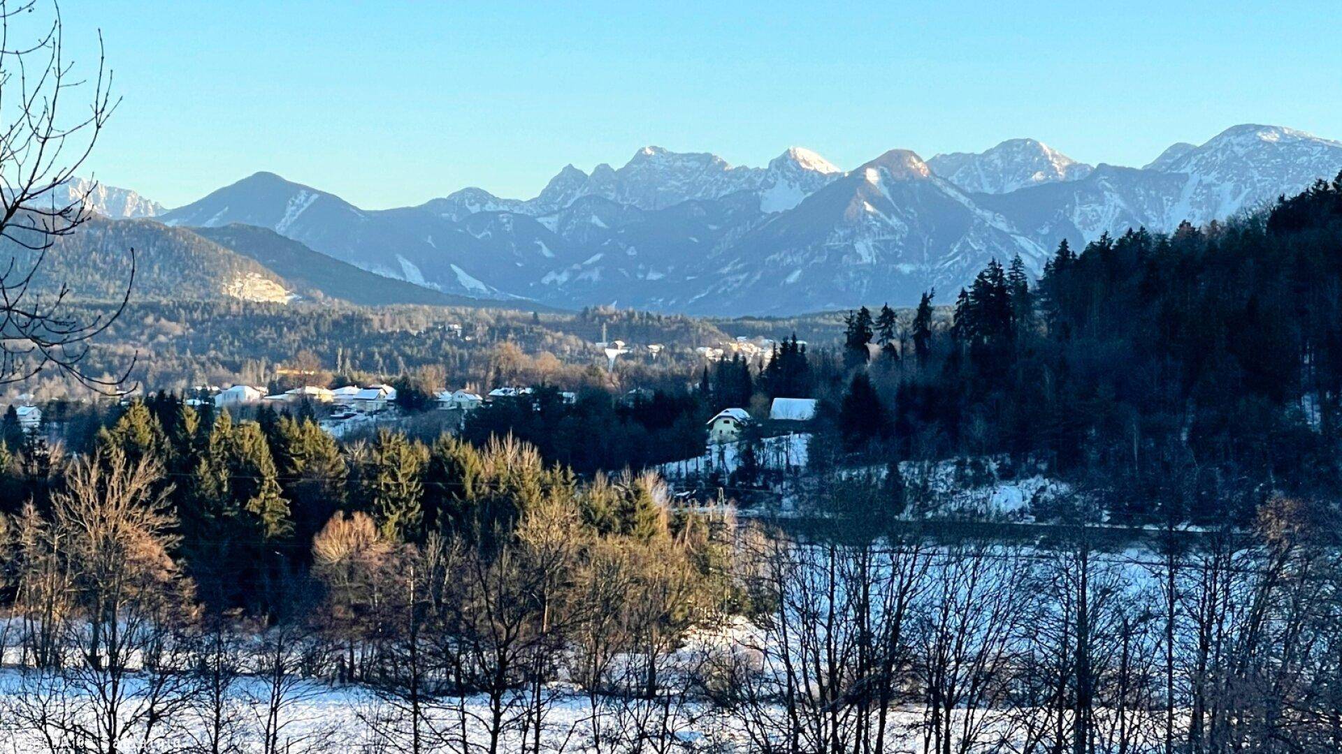 Malerische Winterlandschaft mit schneebedeckten Bergen und Bäumen unter klarem Himmel