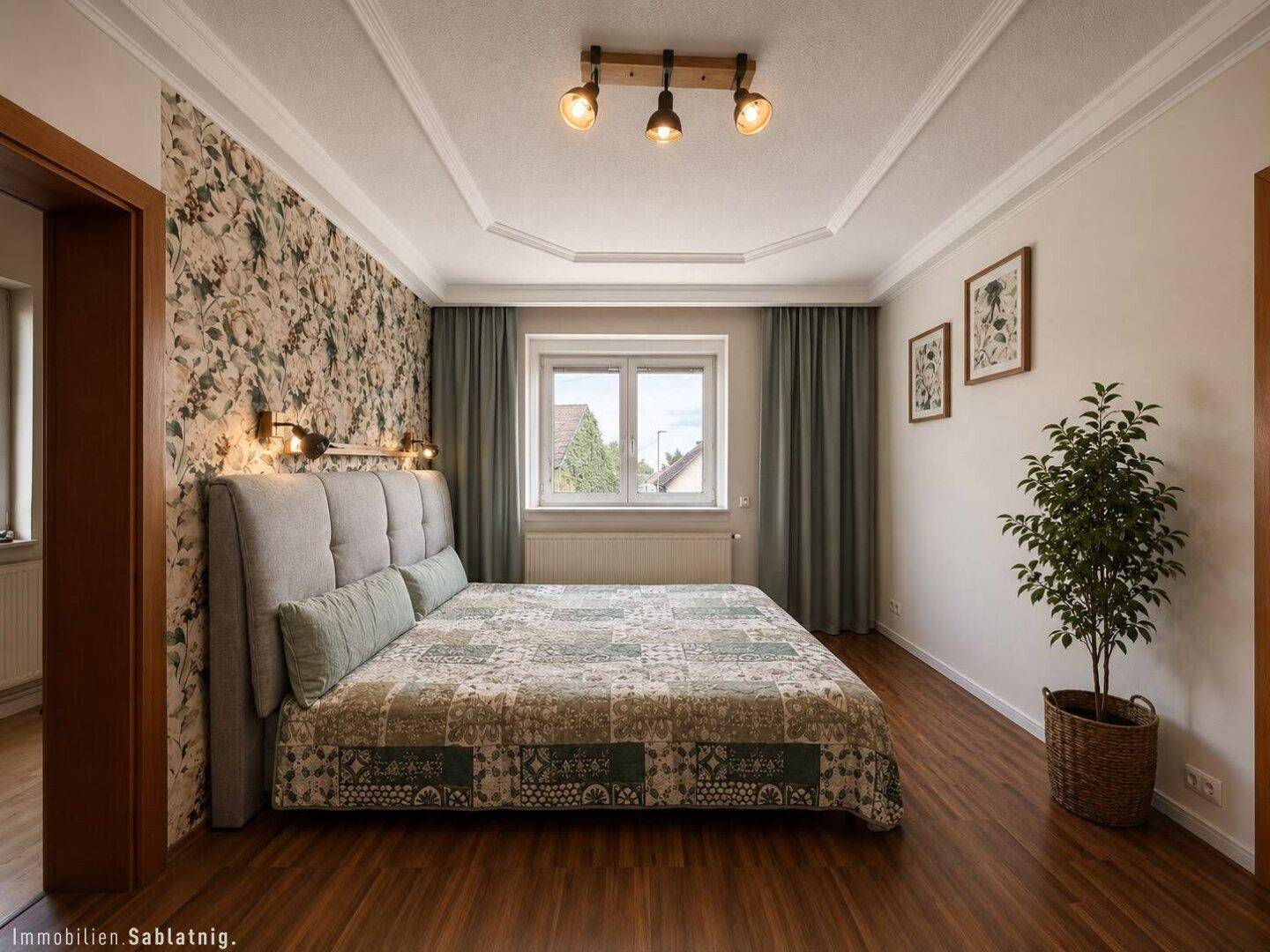 Gemütliches Schlafzimmer mit floraler Tapete, Holzboden und einem großen Bett.