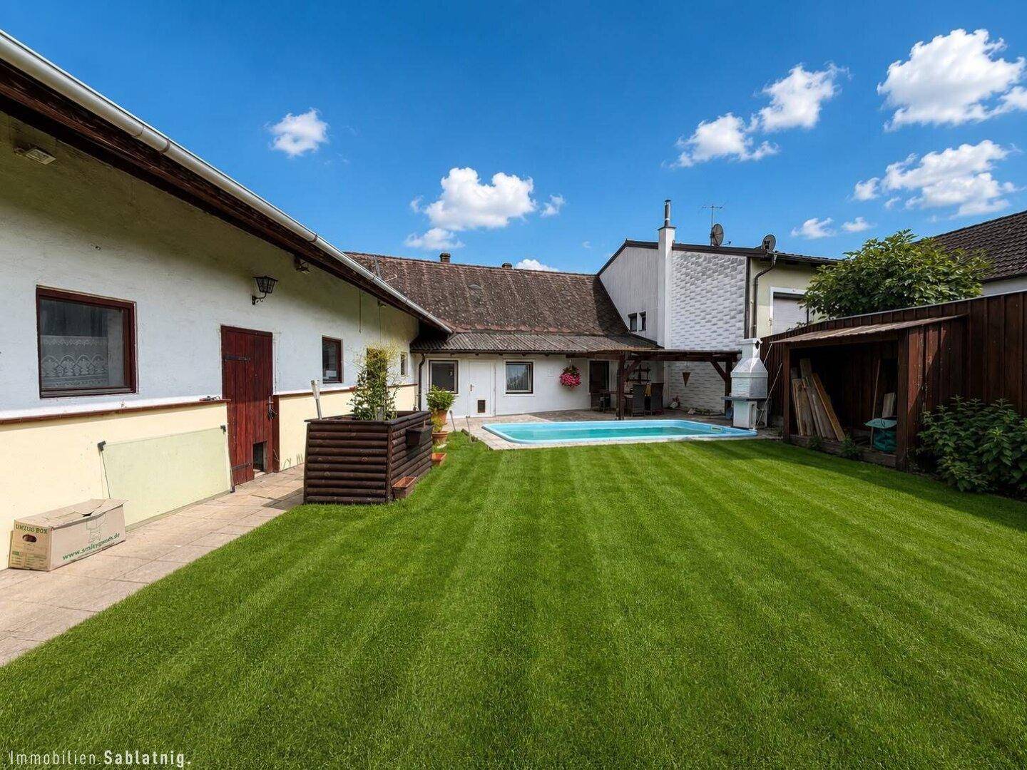 Weitläufiger Garten mit großem Rasen, Swimmingpool und Nebengebäuden.