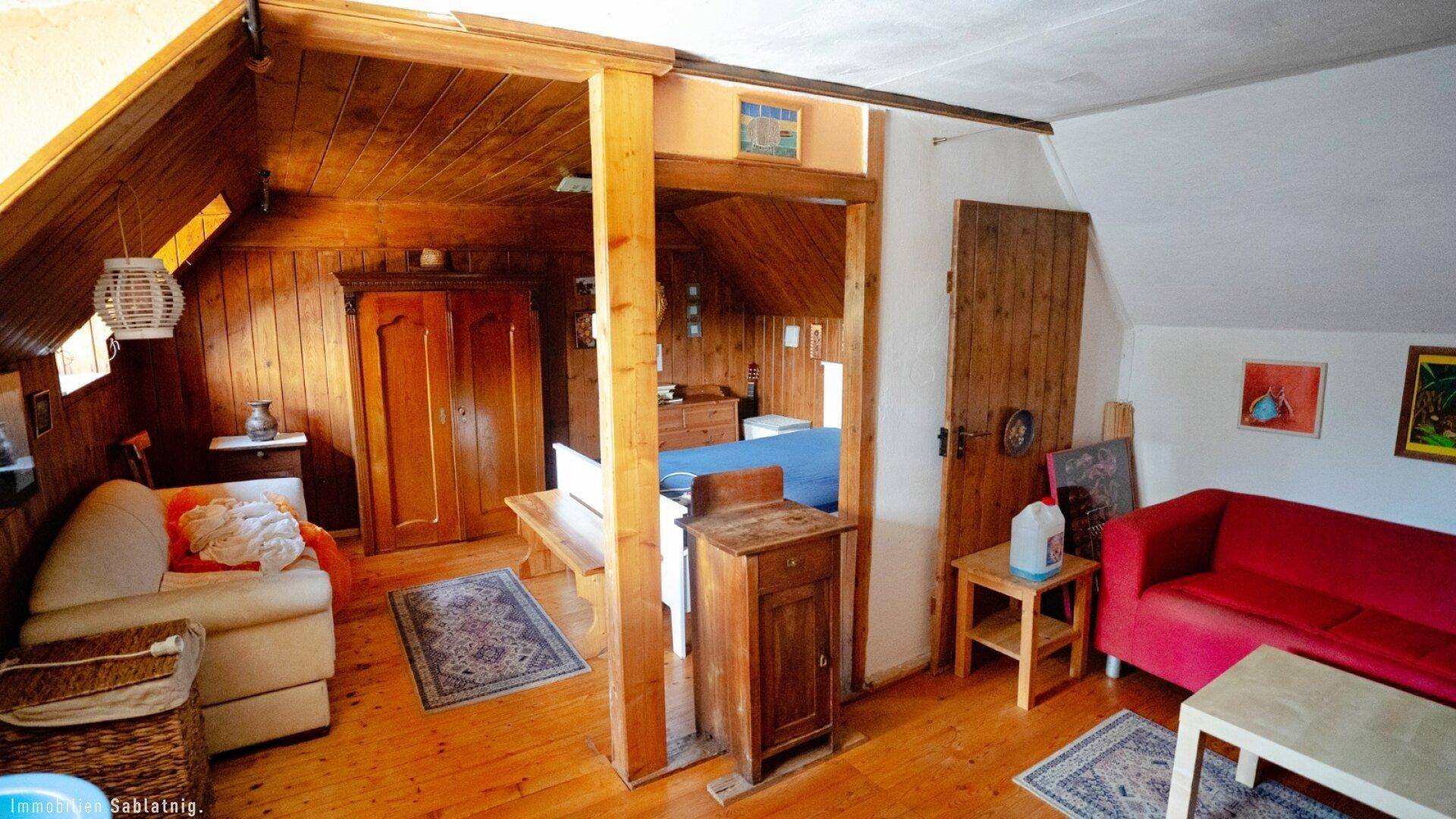 Geräumiger Wohnbereich im Dachgeschoss mit Holzboden, gemütlichen Sofas und Holztäfelung.