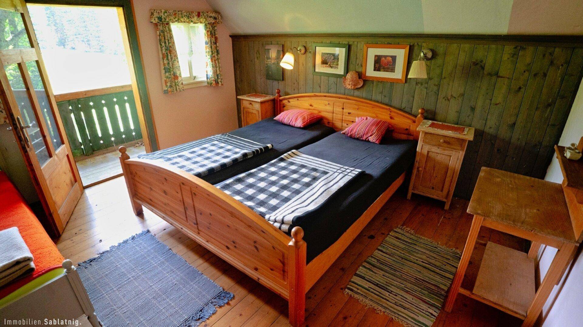 Gemütliches Schlafzimmer mit Holzbetten, Holzwänden und direktem Zugang zum Balkon.