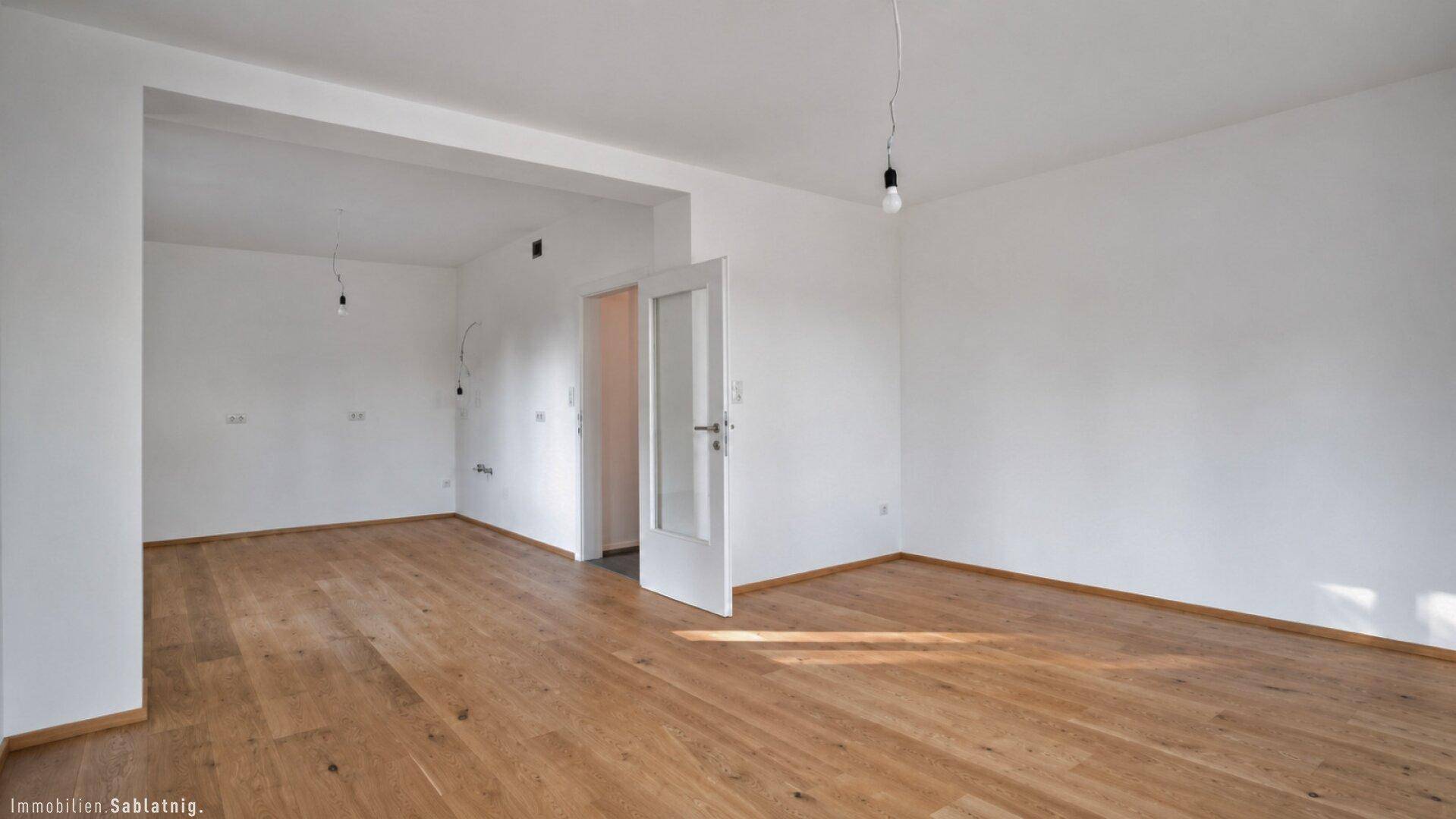 Geräumiges, leeres Wohnzimmer mit hellem Eichenparkett und weiß gestrichenen Wänden.