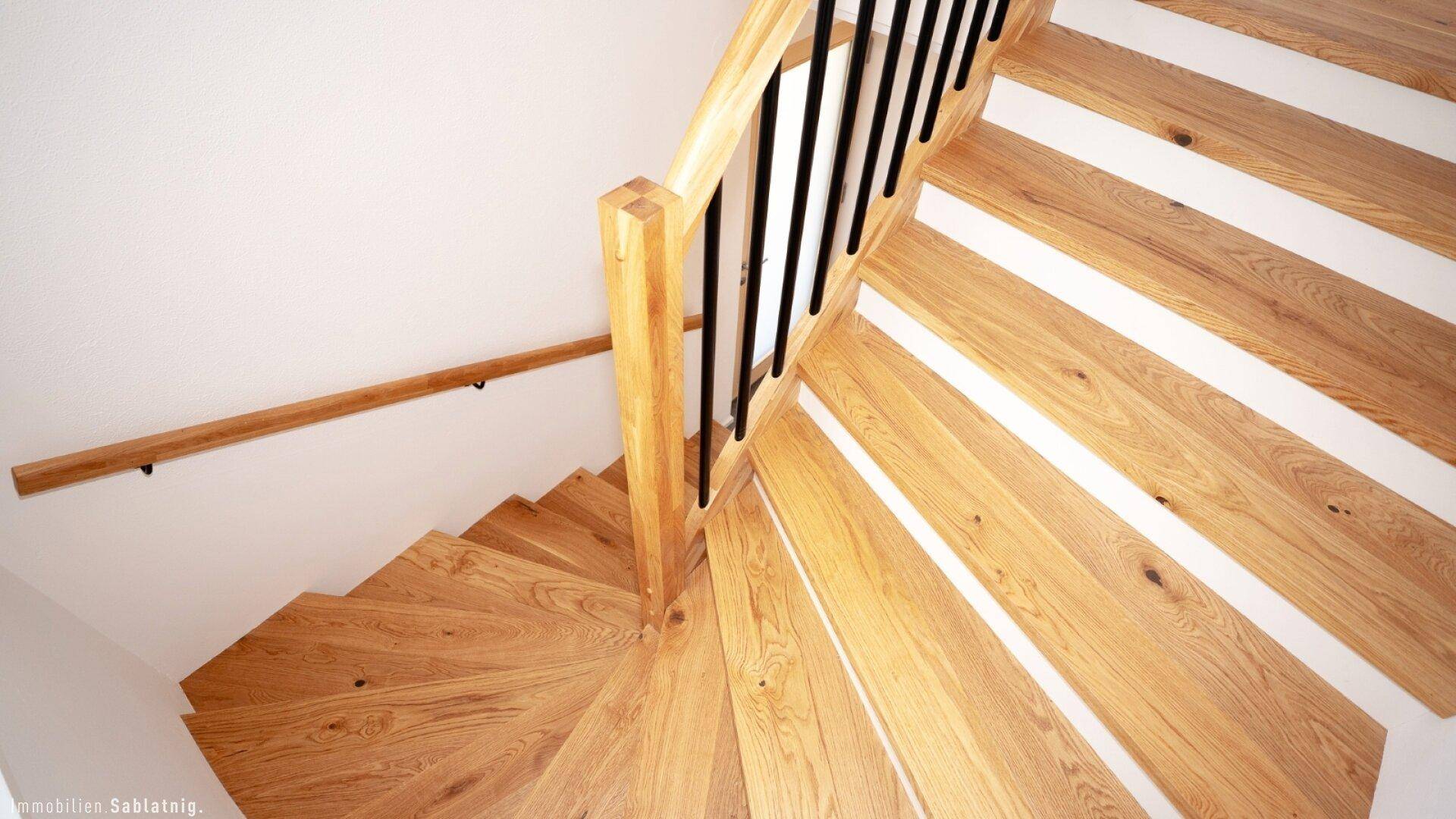 Holztreppe mit elegantem Geländer, die die verschiedenen Etagen des Hauses verbindet.