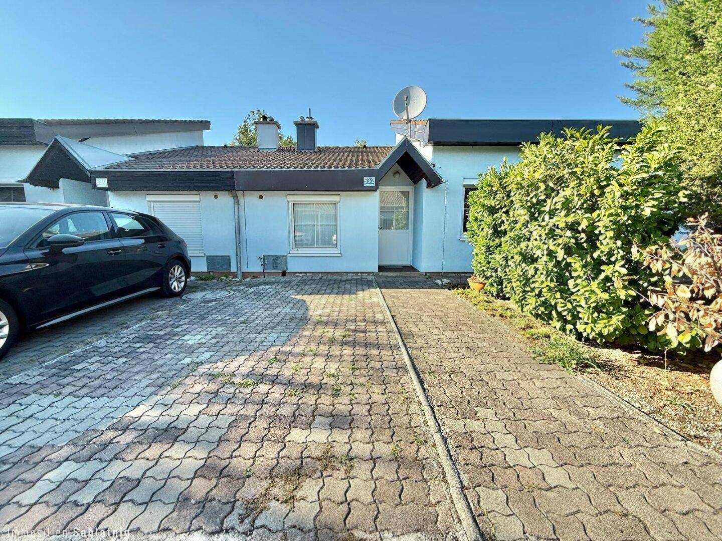 Vorderansicht des Hauses mit gepflasterter Einfahrt und Parkplatz für ein Fahrzeug.