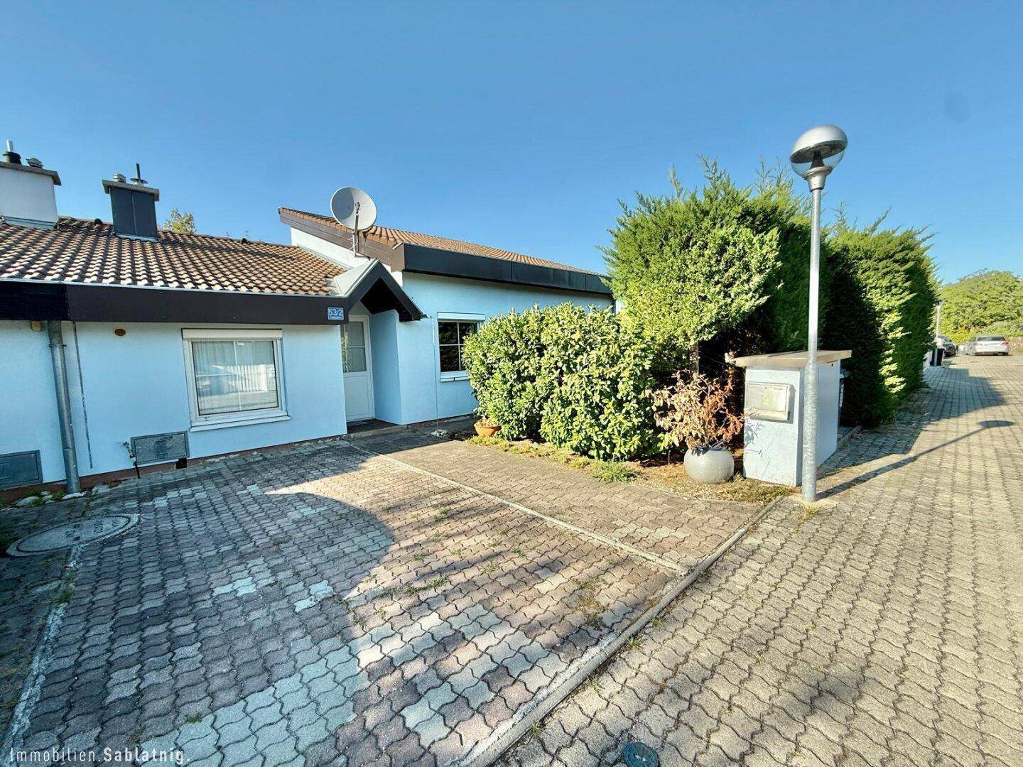 Vorderansicht des Hauses mit gepflasterter Einfahrt und Vorgarten.