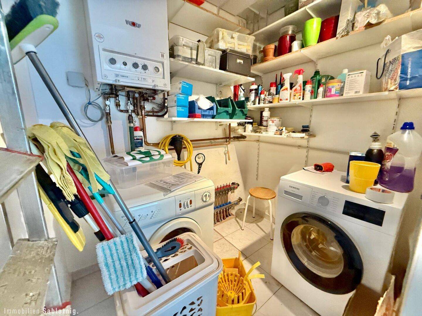 Praktischer Hauswirtschaftsraum mit Waschmaschinen, Regalen und Heizungsanlage.