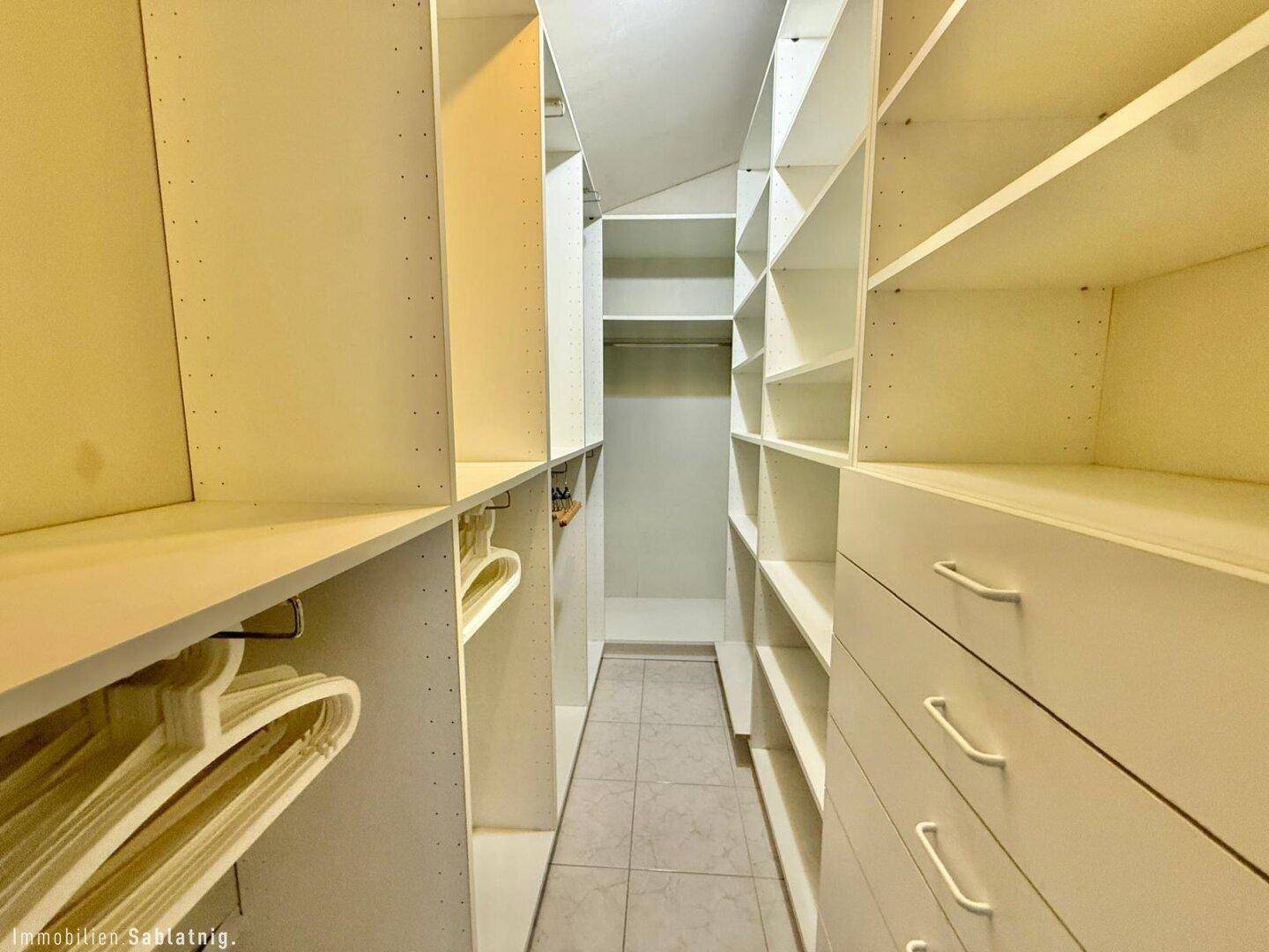 Geräumiger begehbarer Kleiderschrank mit vielen Regalen und Stauraum.