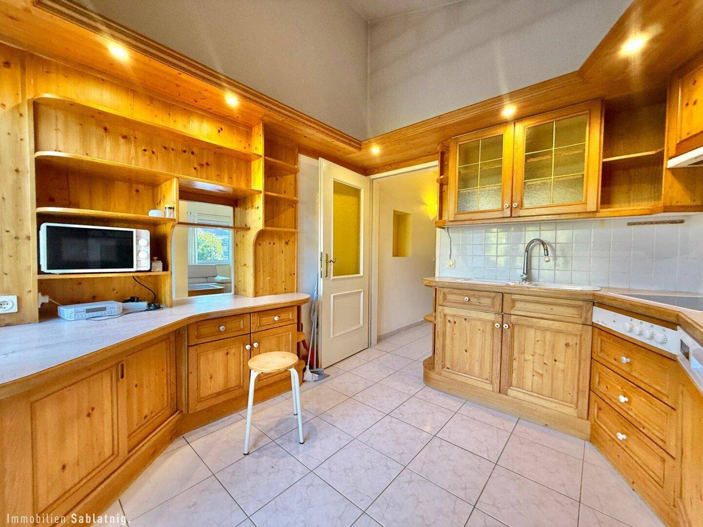 Traditionelle Holzküche mit Einbauschränken, Fliesenboden und integrierten Geräten.