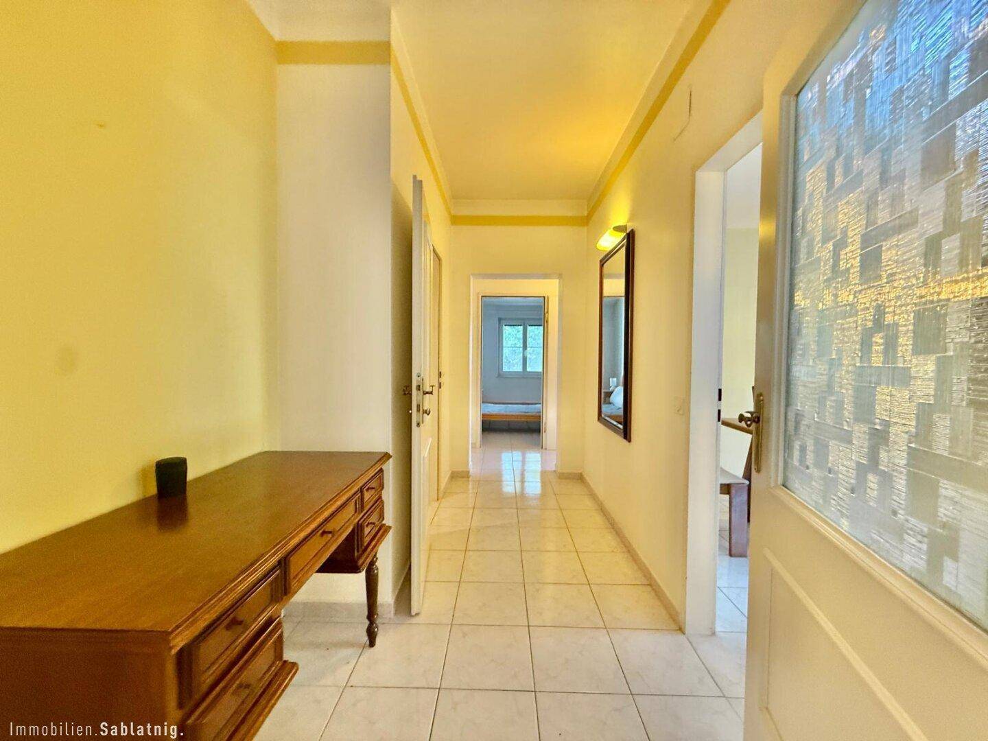 Heller Flur mit Fliesenboden und Zugang zu weiteren Räumen im Haus.