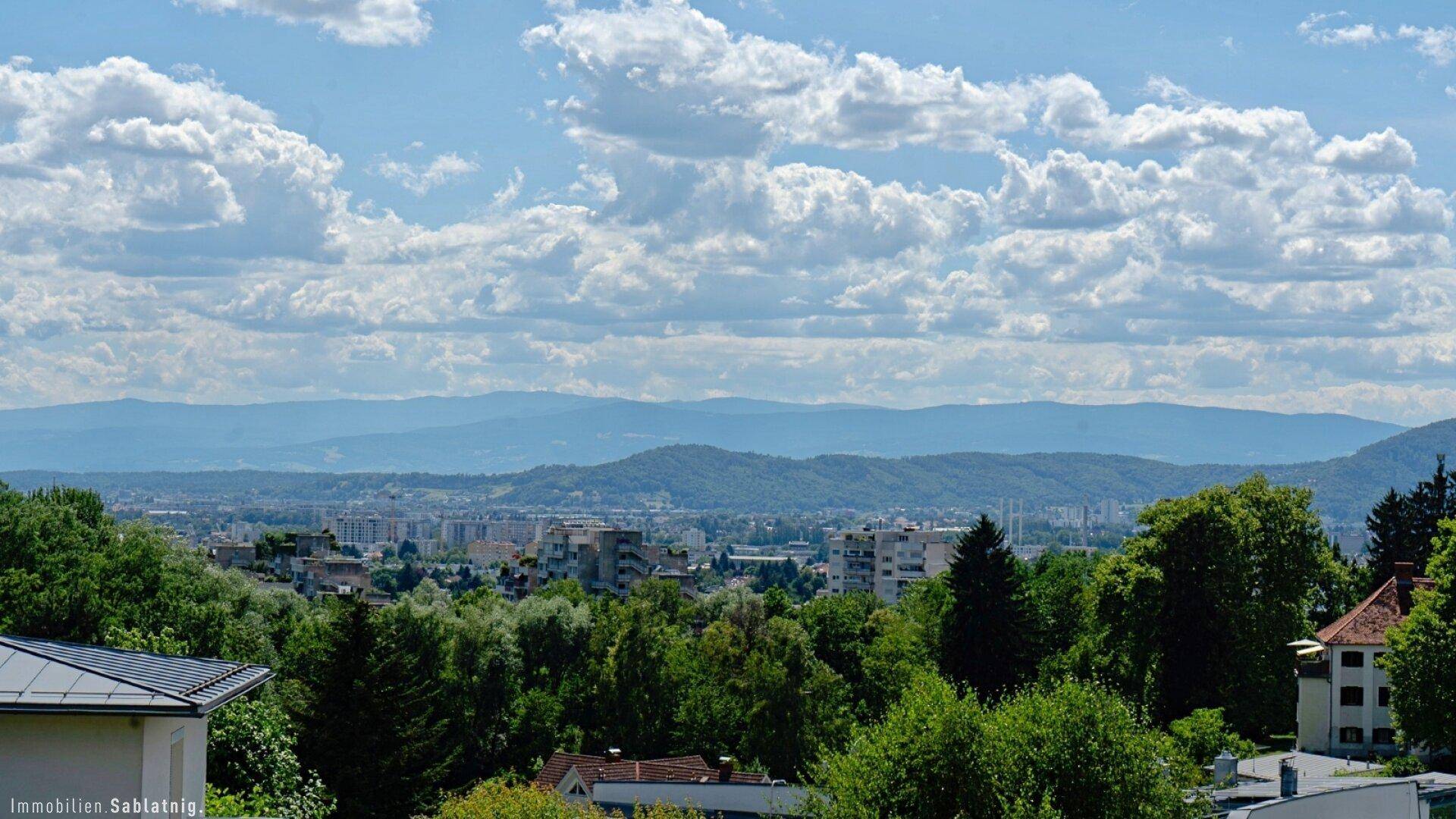 Panoramablick über die Stadt und die umliegende Landschaft mit Bergen am Horizont.