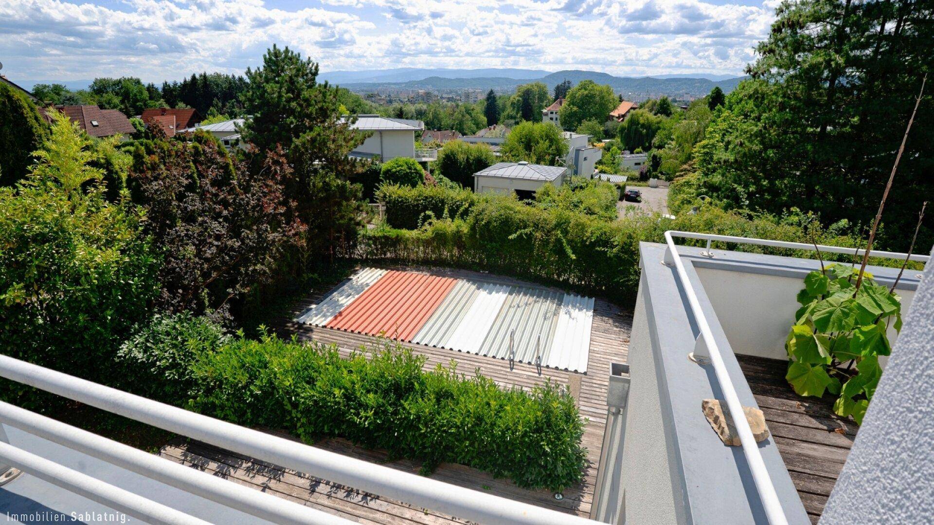 Gartenbereich mit Pool und Holzdeck, umgeben von Hecken und Bäumen.