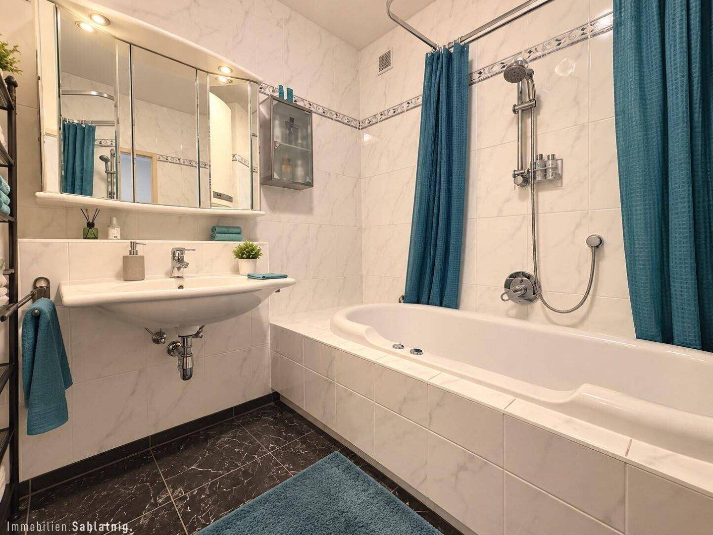 Helles Badezimmer mit Badewanne, Duschvorhang und Spiegelschrank über dem Waschbecken.