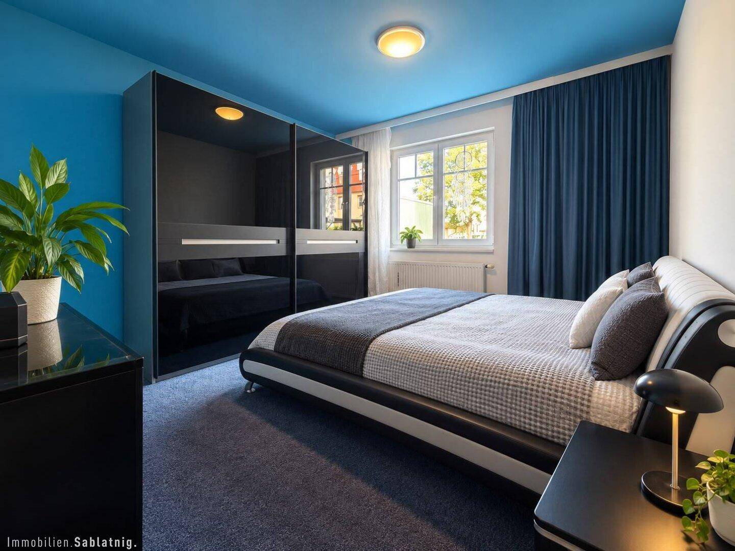 Modernes Schlafzimmer mit blauen Wänden, Teppichboden und großem Bett.