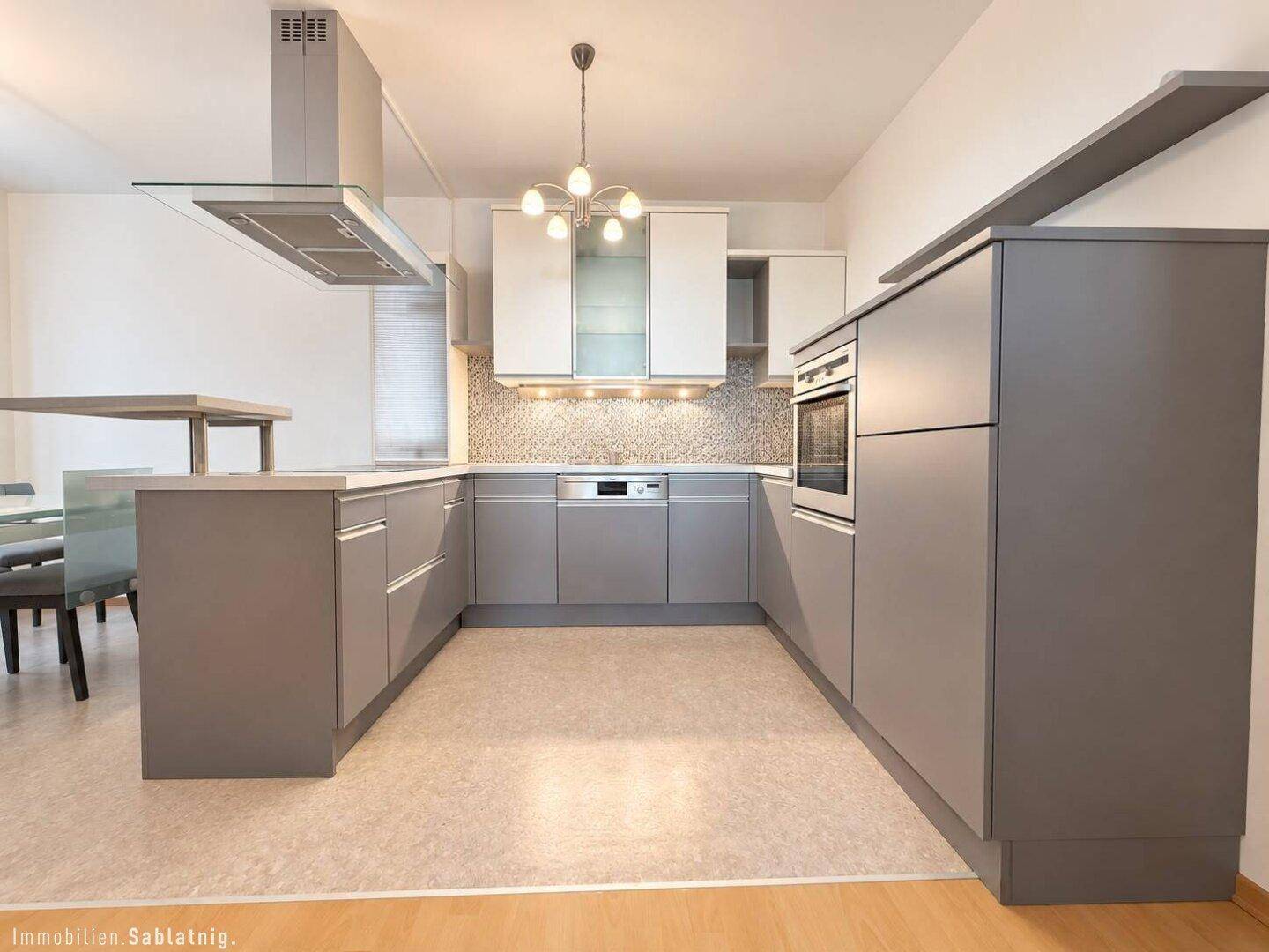 Moderne Einbauküche in Grau und Weiß mit integrierten Geräten und Dunstabzugshaube.