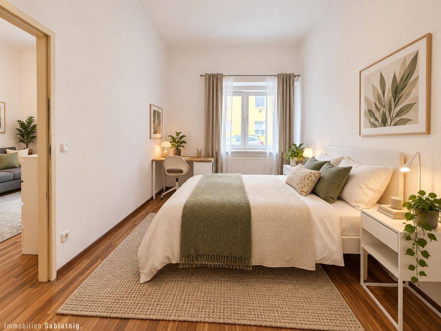 Helles Schlafzimmer mit Doppelbett, Schreibtisch und Parkettboden, mit Blick ins Grüne.