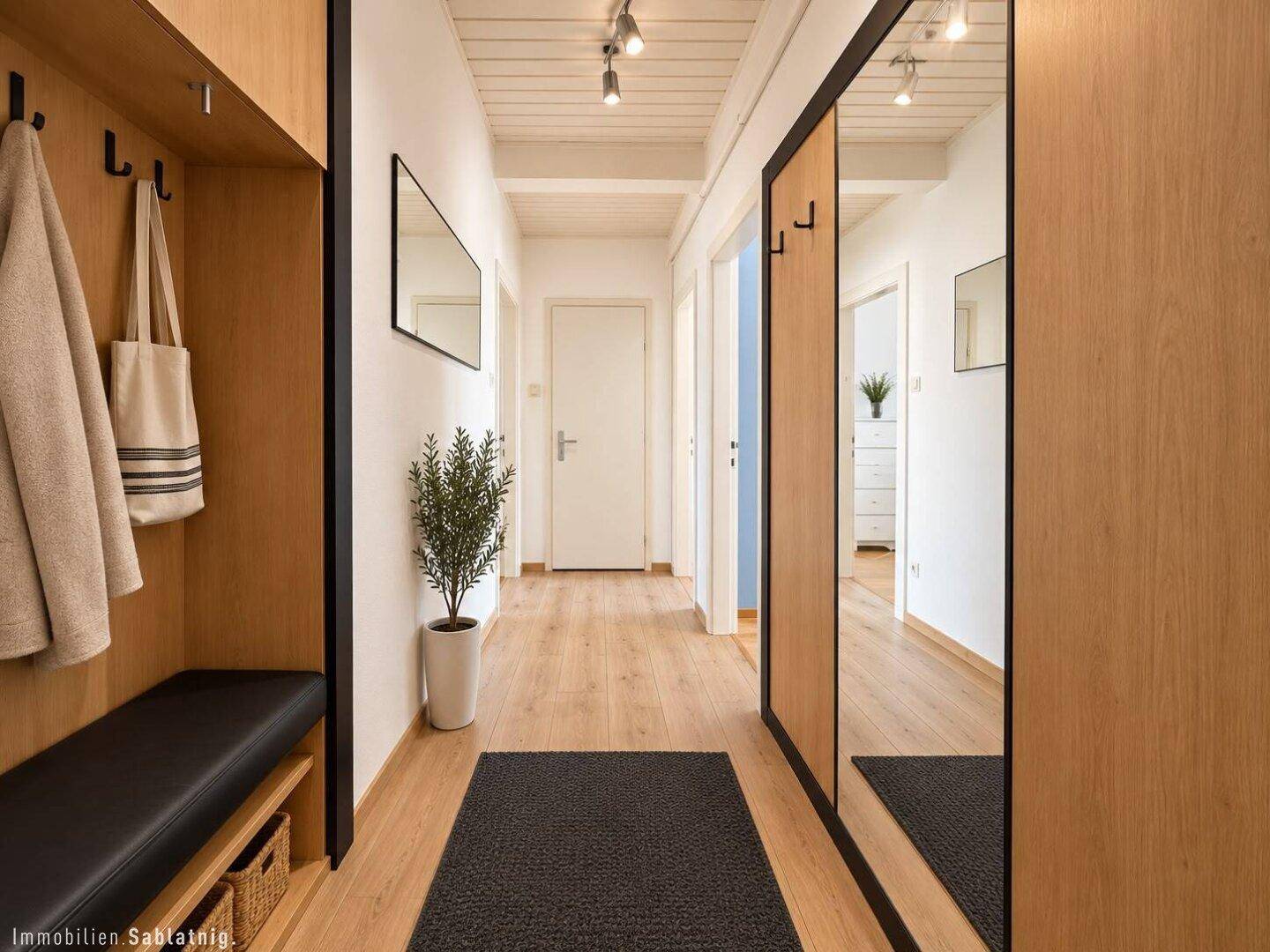 Heller Flur mit Holzverkleidung, Garderobe, Spiegeln und Holzbalkendecke.