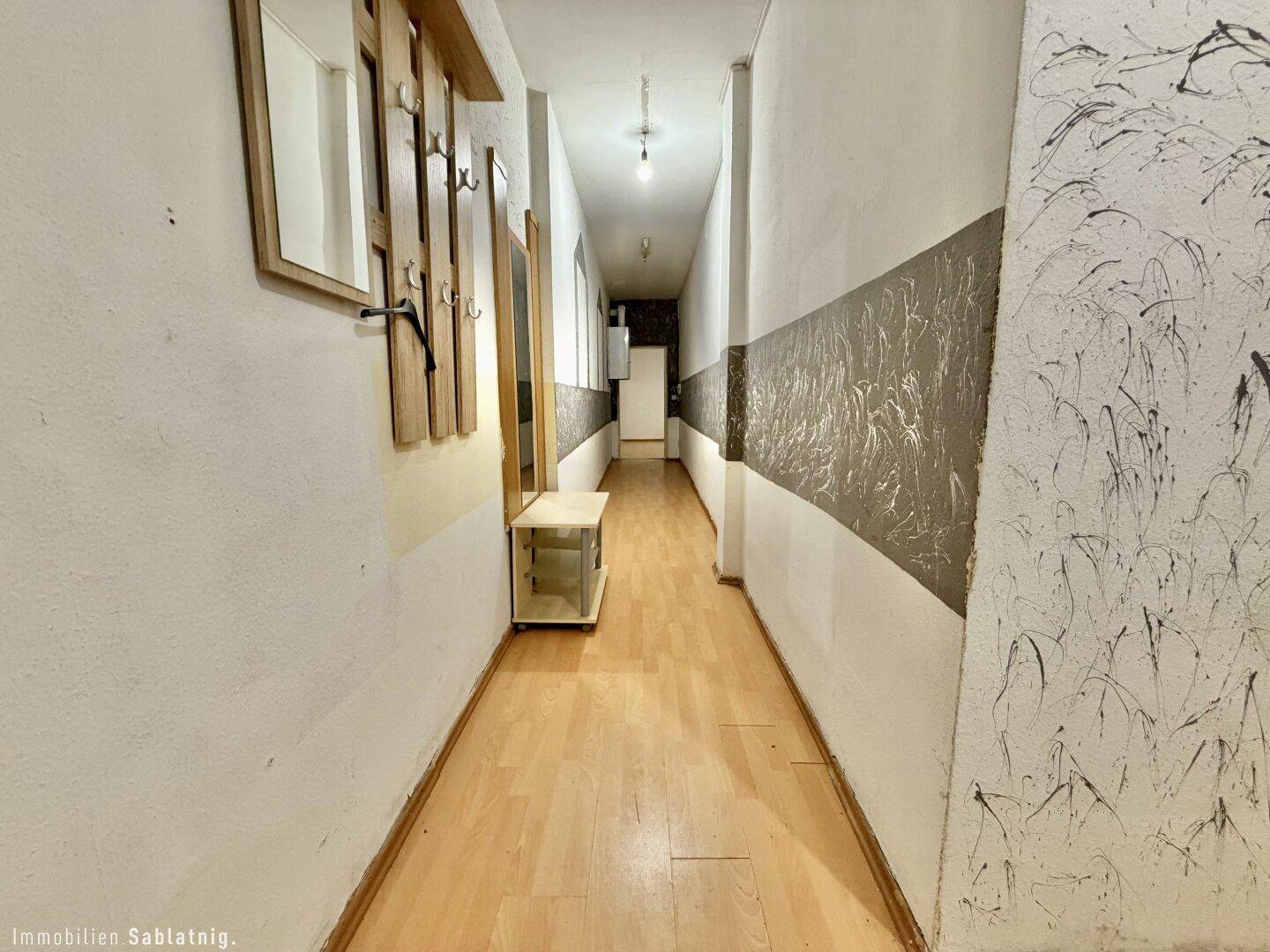 Gangbereich mit Garderobe, Spiegel und strukturierten Tapeten.