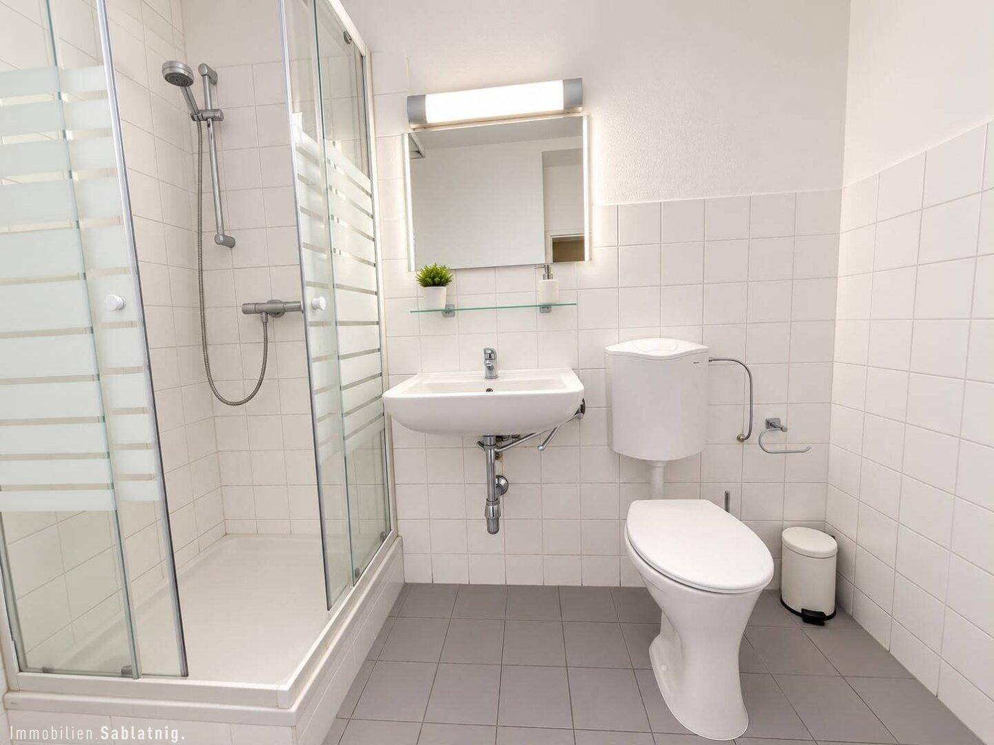 Modernes Badezimmer mit Duschkabine, WC, Waschbecken und weißen Fliesen.