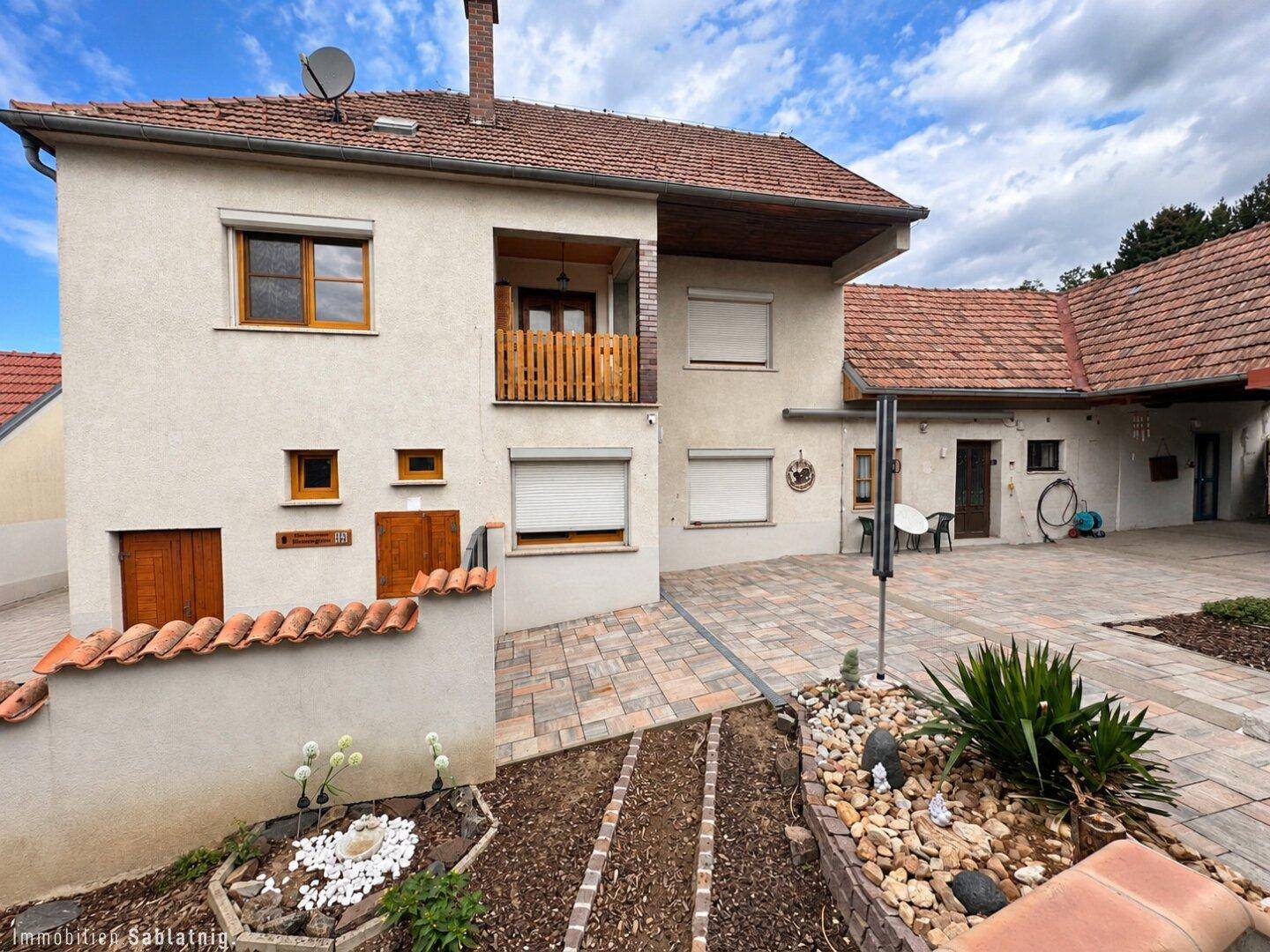 Hinterhofbereich mit gepflastertem Innenhof, kleinem Gartenbeet und Zugang zum Haus.