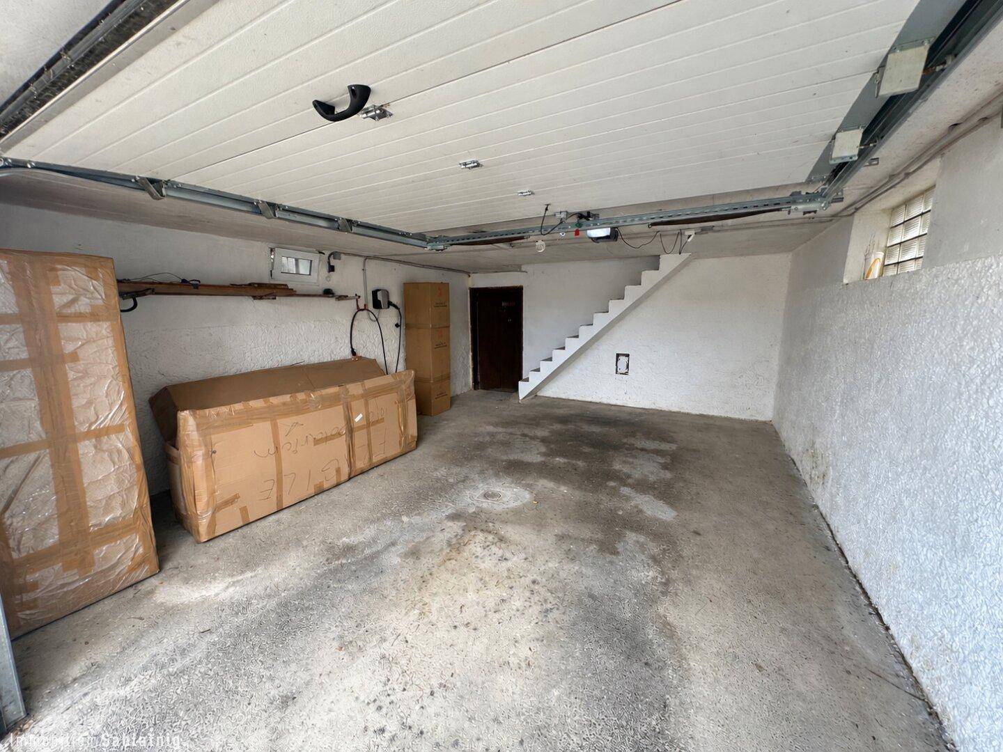 Geräumige Garage mit Betonboden, Stauraum und Treppe zum oberen Bereich.