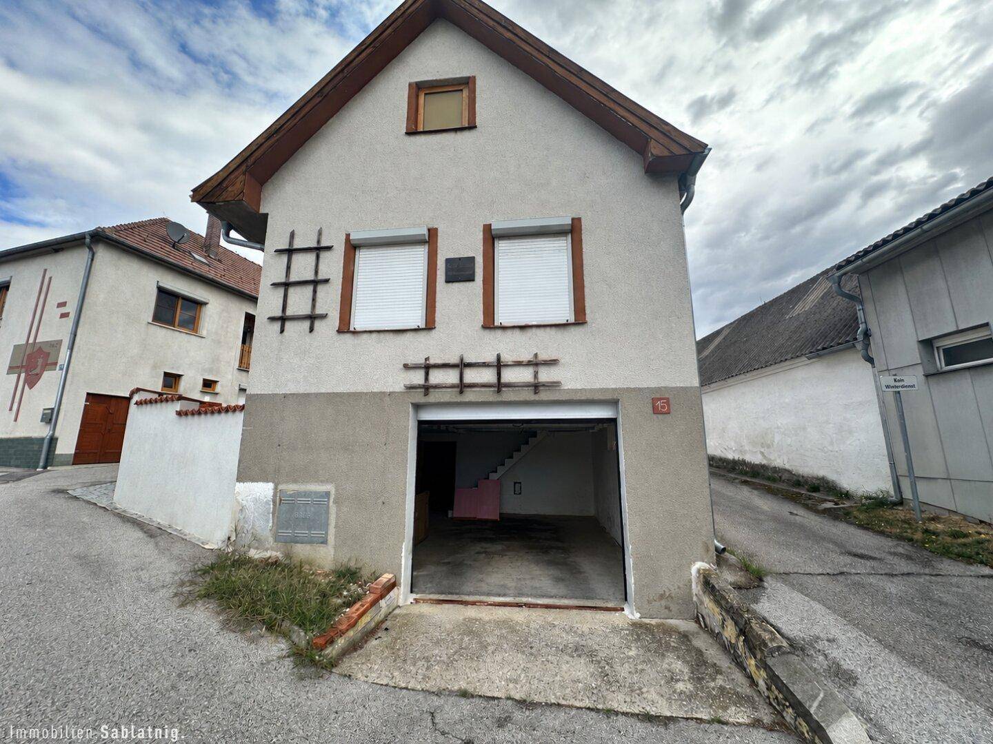 Einfamilienhaus mit integrierter Garage und Rollläden an den Fenstern.
