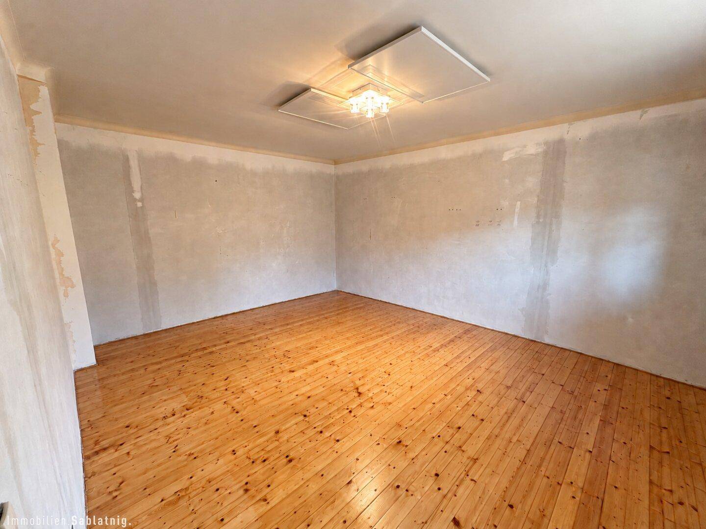 Schlafzimmer mit Holzdielenboden und moderner Deckenbeleuchtung, bereit für die Gestaltung.