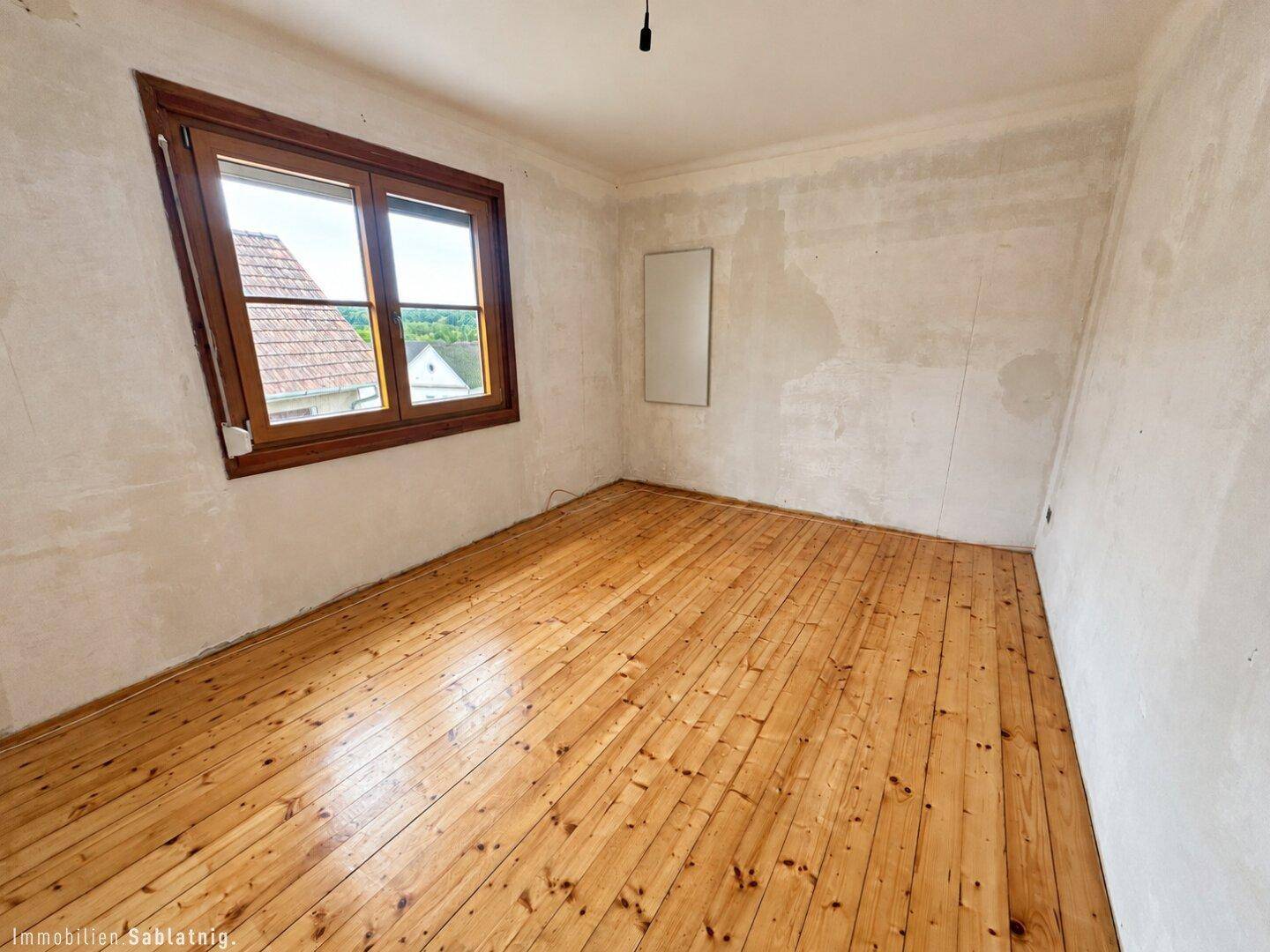 Geräumiges Schlafzimmer mit Holzdielenboden und unfertigen Wänden, bereit zur Renovierung.