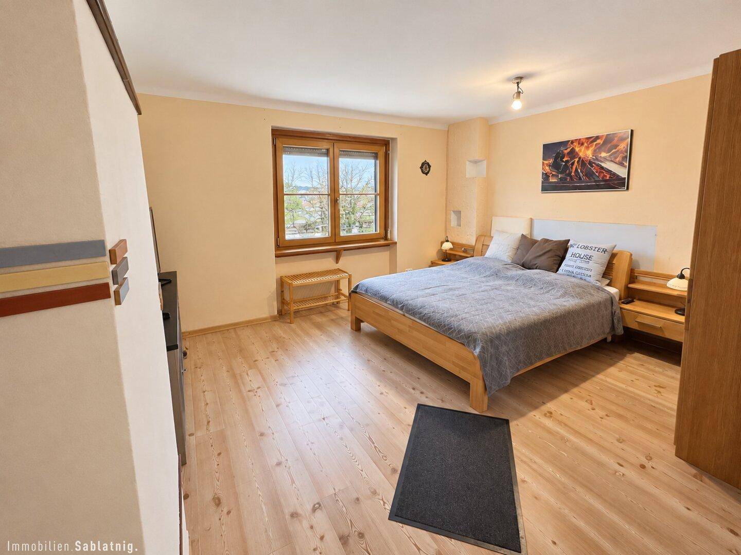Helles Schlafzimmer mit Holzboden, Doppelbett und Blick ins Grüne.