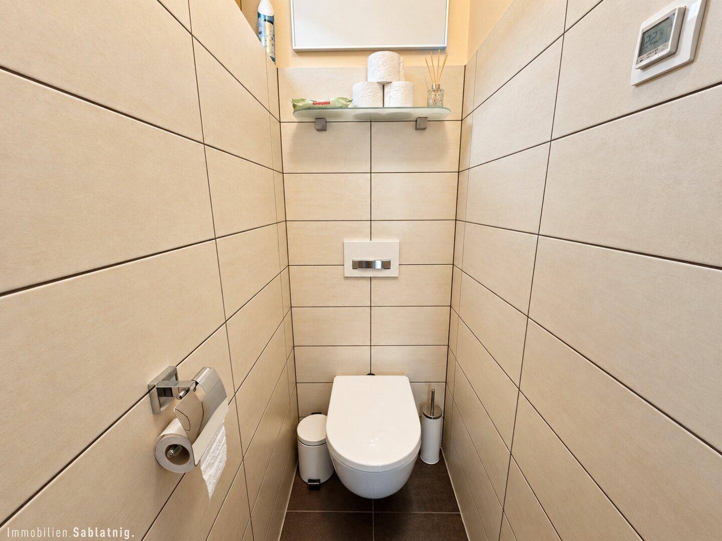 Modernes Gäste-WC mit beigefarbenen Fliesen und wandhängendem WC.