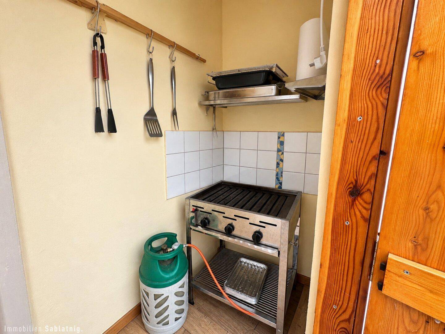 Kleiner Bereich mit Gasgrill und Utensilien, ideal für Outdoor-Kochen.