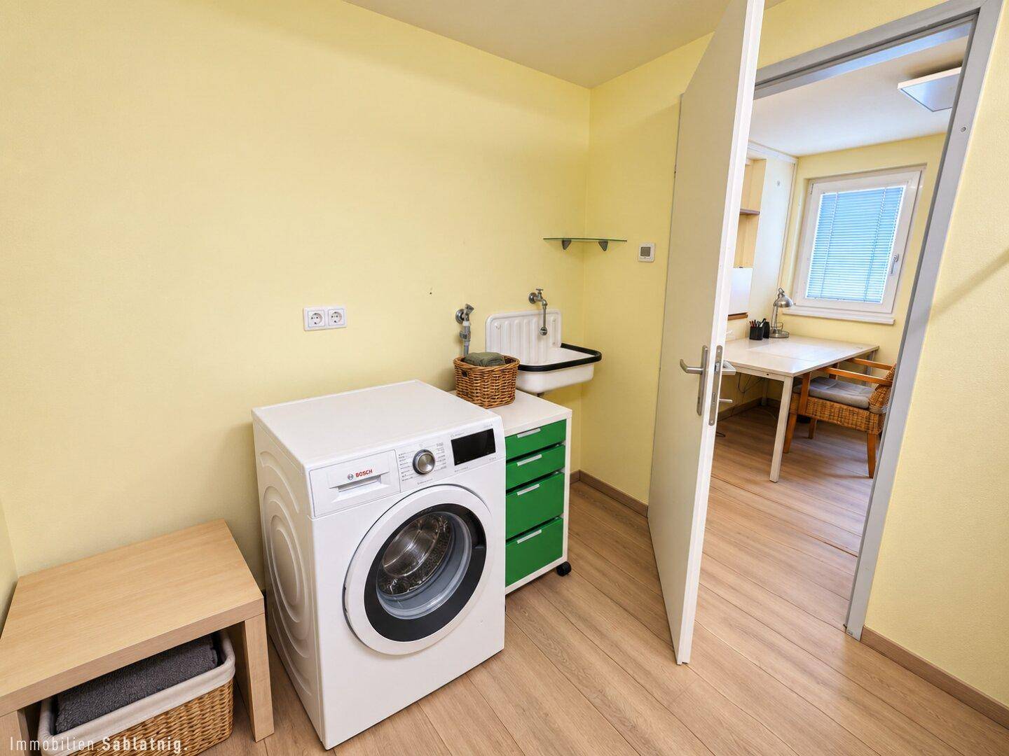 Praktischer Hauswirtschaftsraum mit Waschmaschine, Waschbecken und Stauraum.