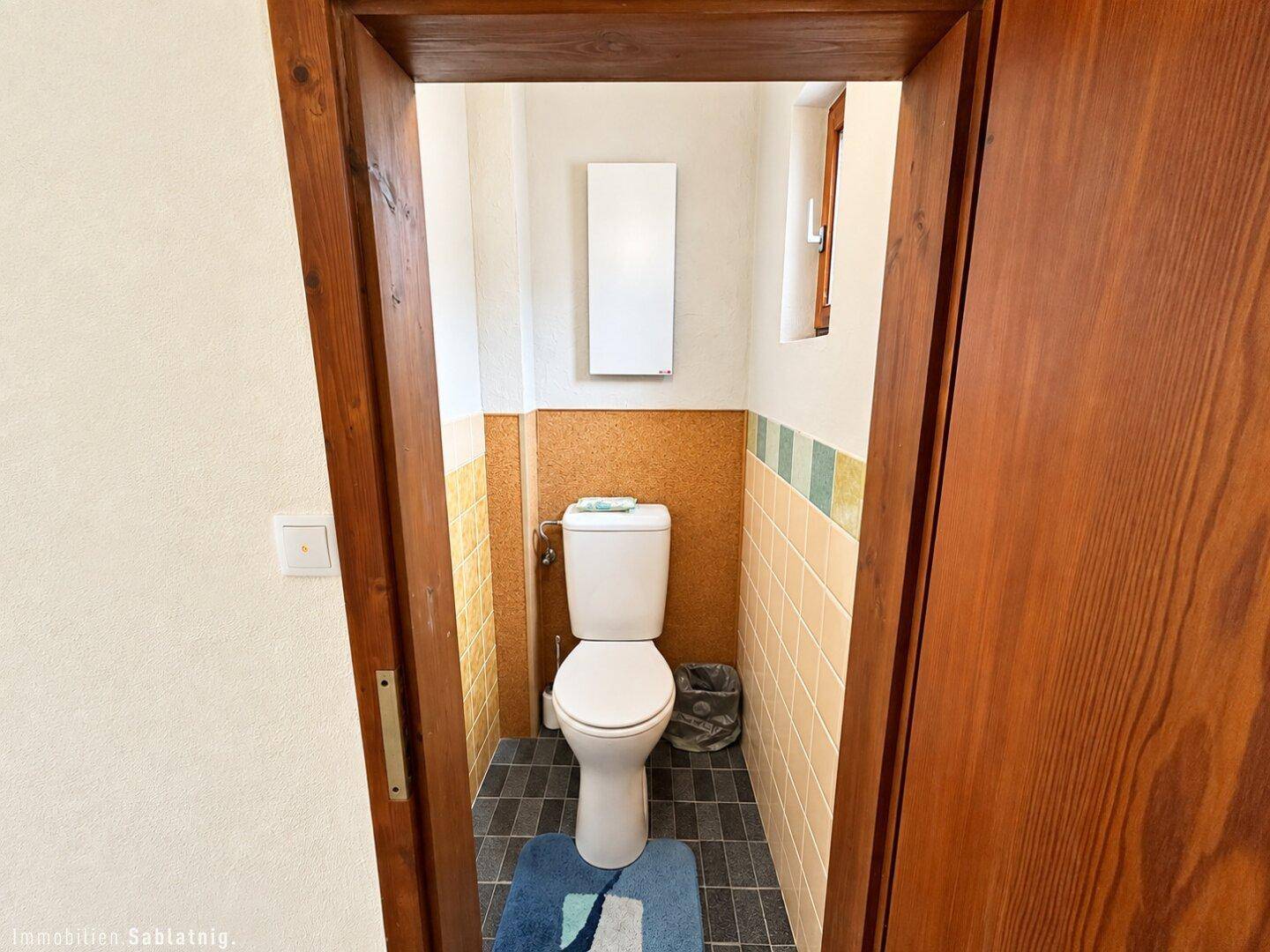 Kleines Gäste-WC mit Wandheizung und farbigen Fliesen an den Wänden.