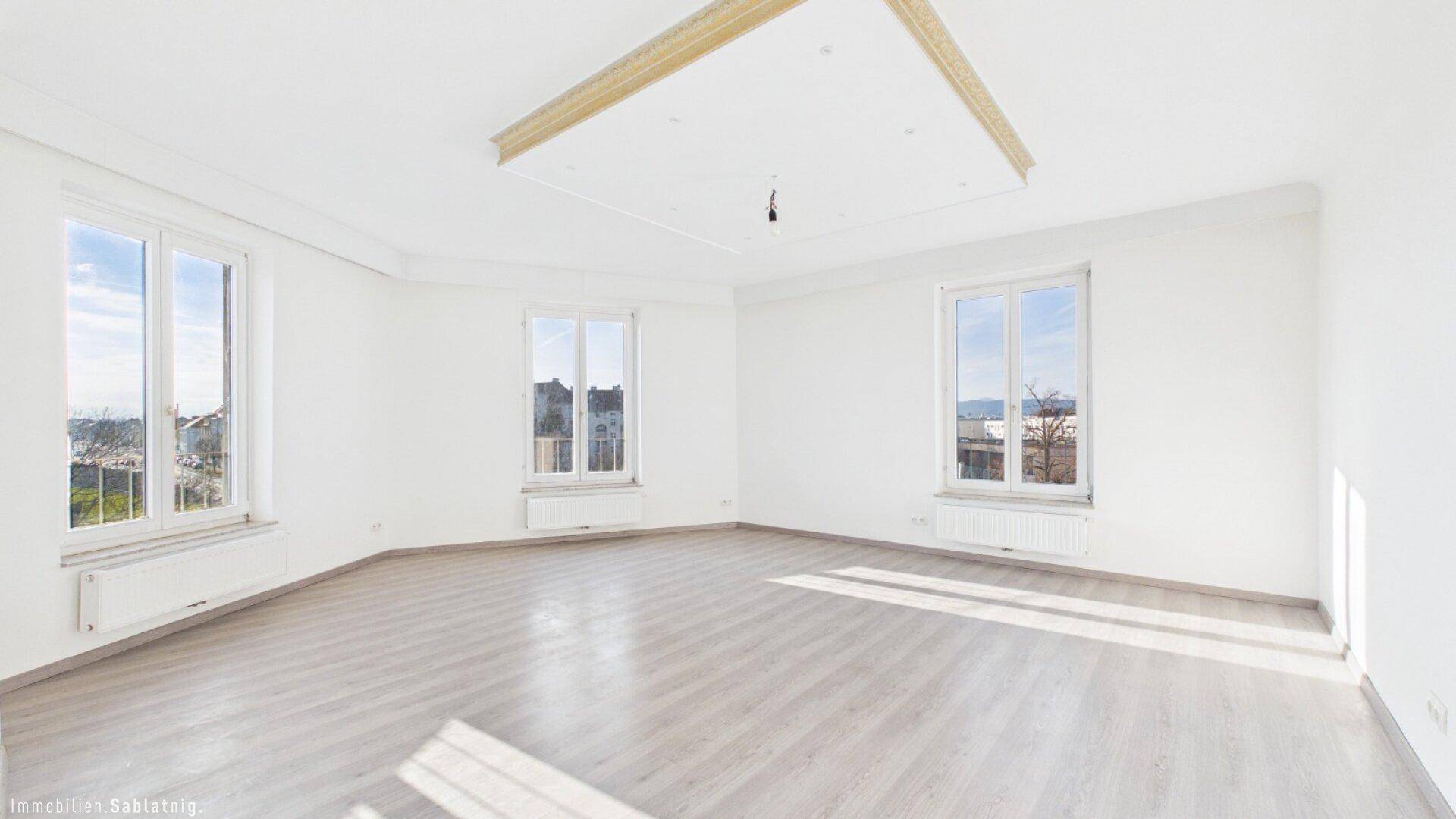 Geräumiges, helles Zimmer mit Laminatboden und drei Fenstern, die eine weite Aussicht bieten.