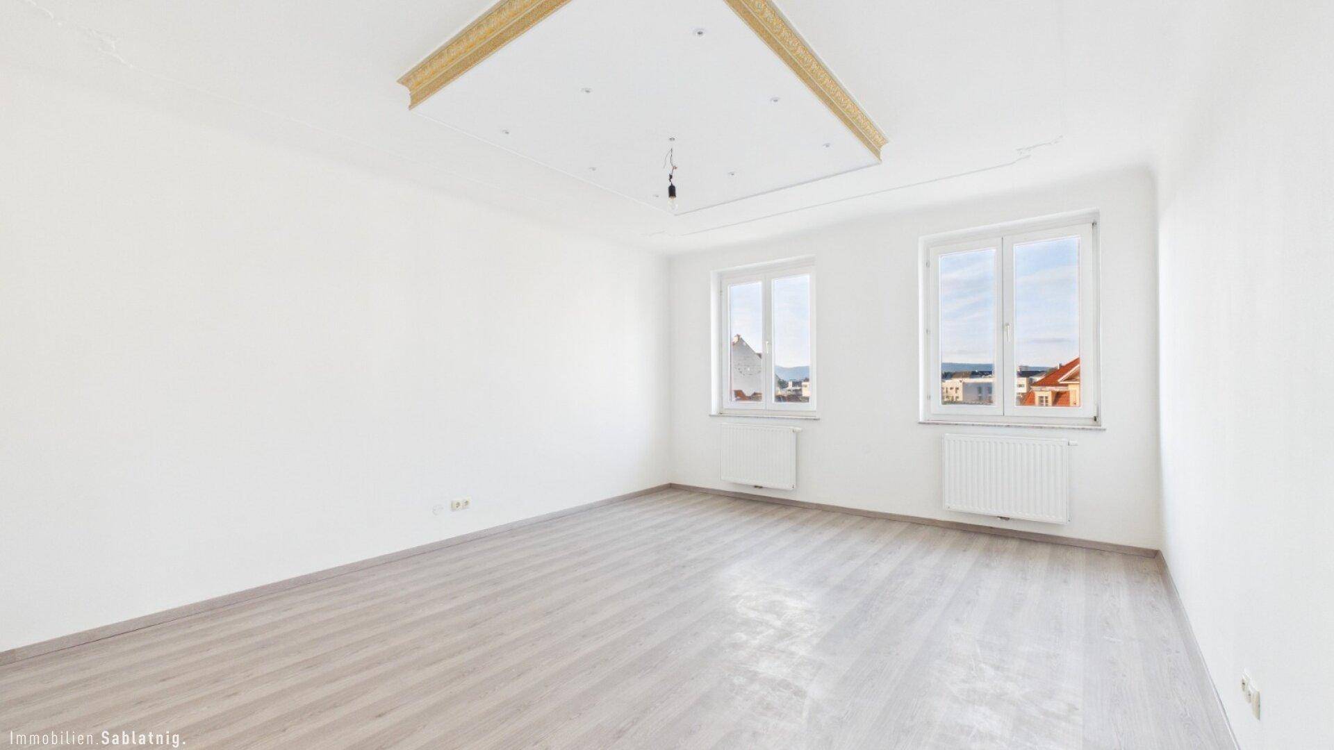 Geräumiges, helles Zimmer mit Laminatboden und zwei Fenstern, ideal für individuelle Gestaltung.