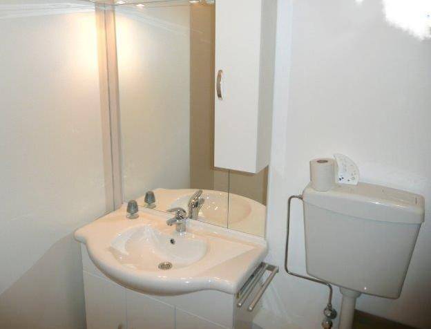 Kleines Badezimmer mit Waschbecken, Spiegel, Spiegelschrank und Toilette.
