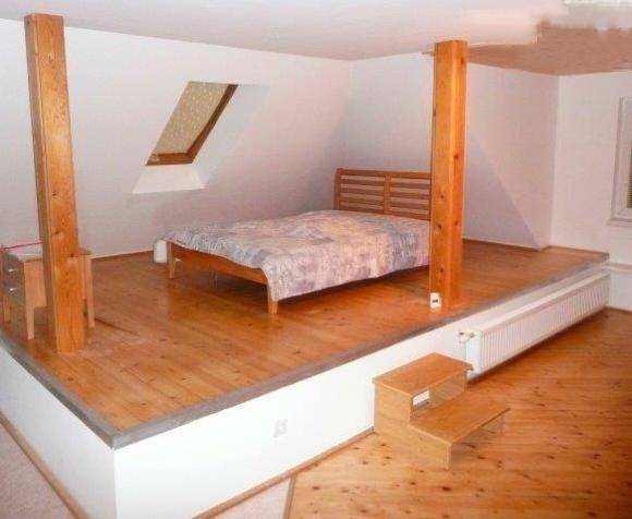 Gemütliches Schlafzimmer im Dachgeschoss mit Holzboden, Dachfenster und erhöhtem Schlafbereich.