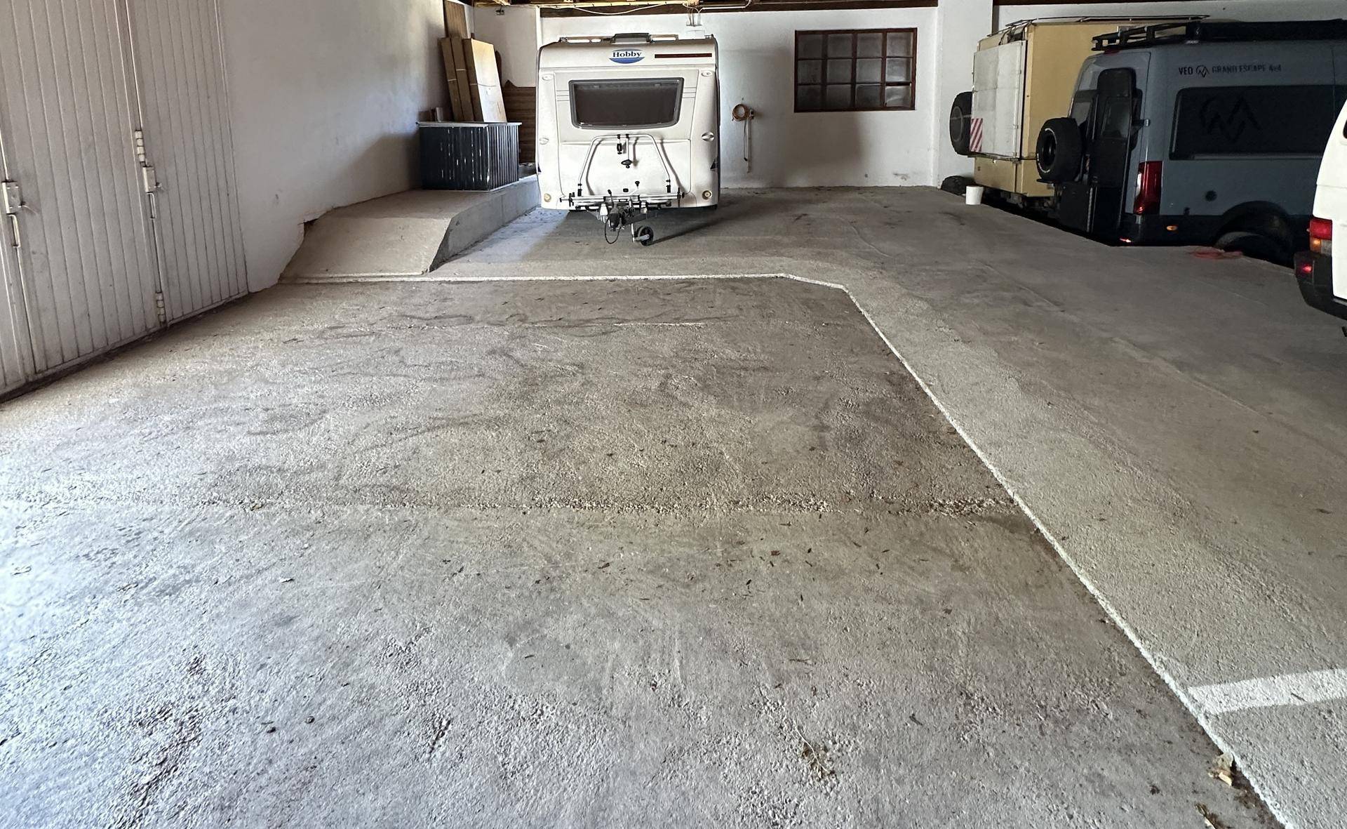 Saubere und funktionale Garage mit Betonboden und einer kleinen Rampe im Hintergrund.