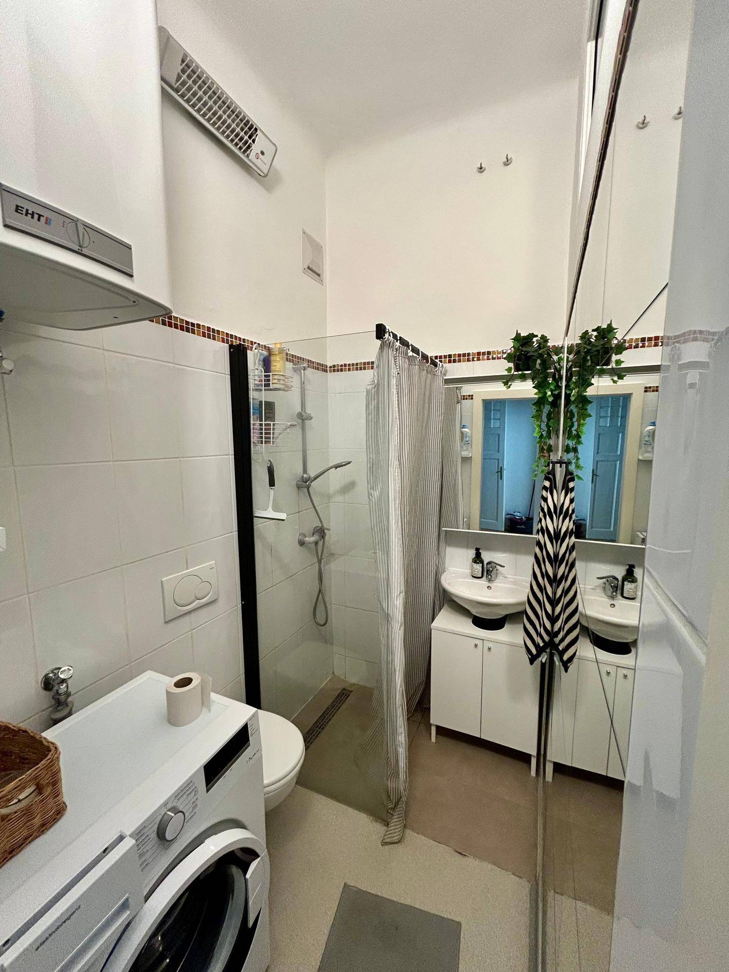 Modernes Badezimmer mit Dusche, Toilette, Doppelwaschbecken und Spiegeln.