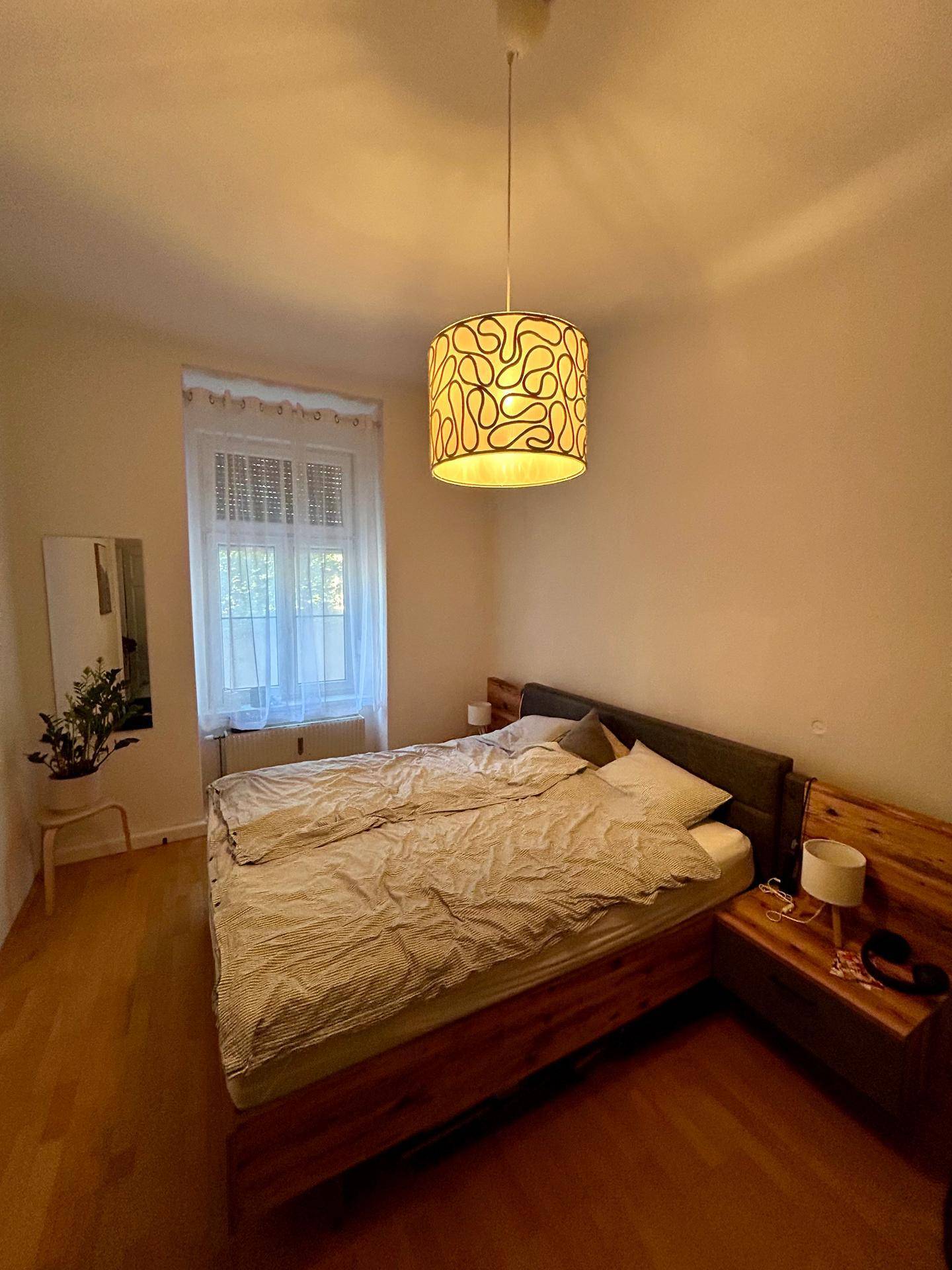 Gemütliches Schlafzimmer mit Holzbett, Nachttischen und einem Fenster für natürliches Licht.