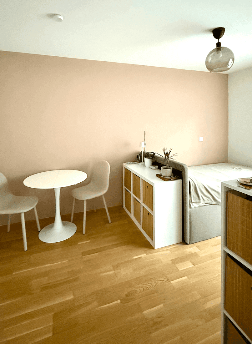 Gemütliches Schlafzimmer mit hellem Holzboden, kleinem Esstisch und moderner Einrichtung.