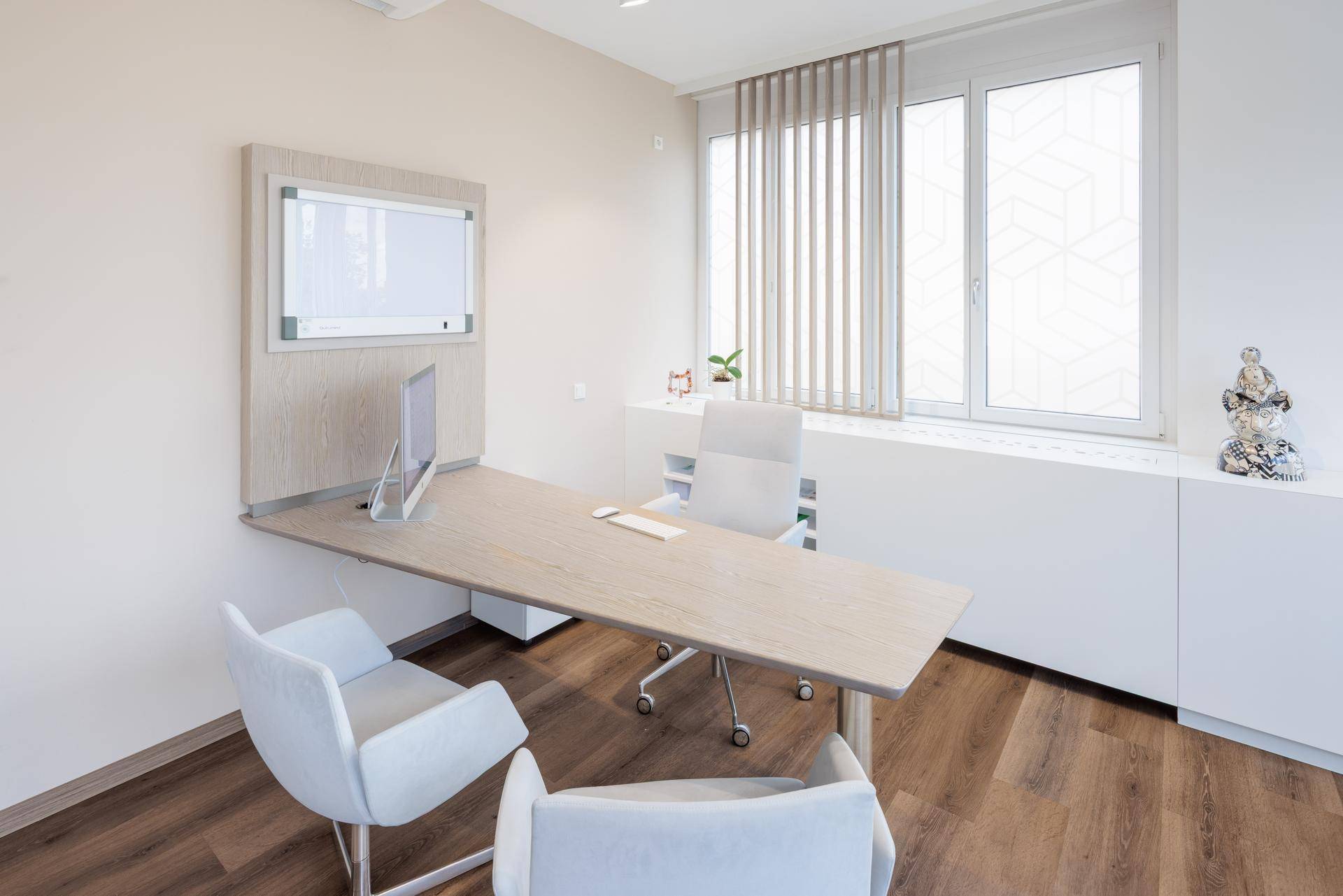 Helles Einzelbüro mit modernem Schreibtisch, Bürostuhl und großen Fenstern, die einen grünen Ausblick bieten.
