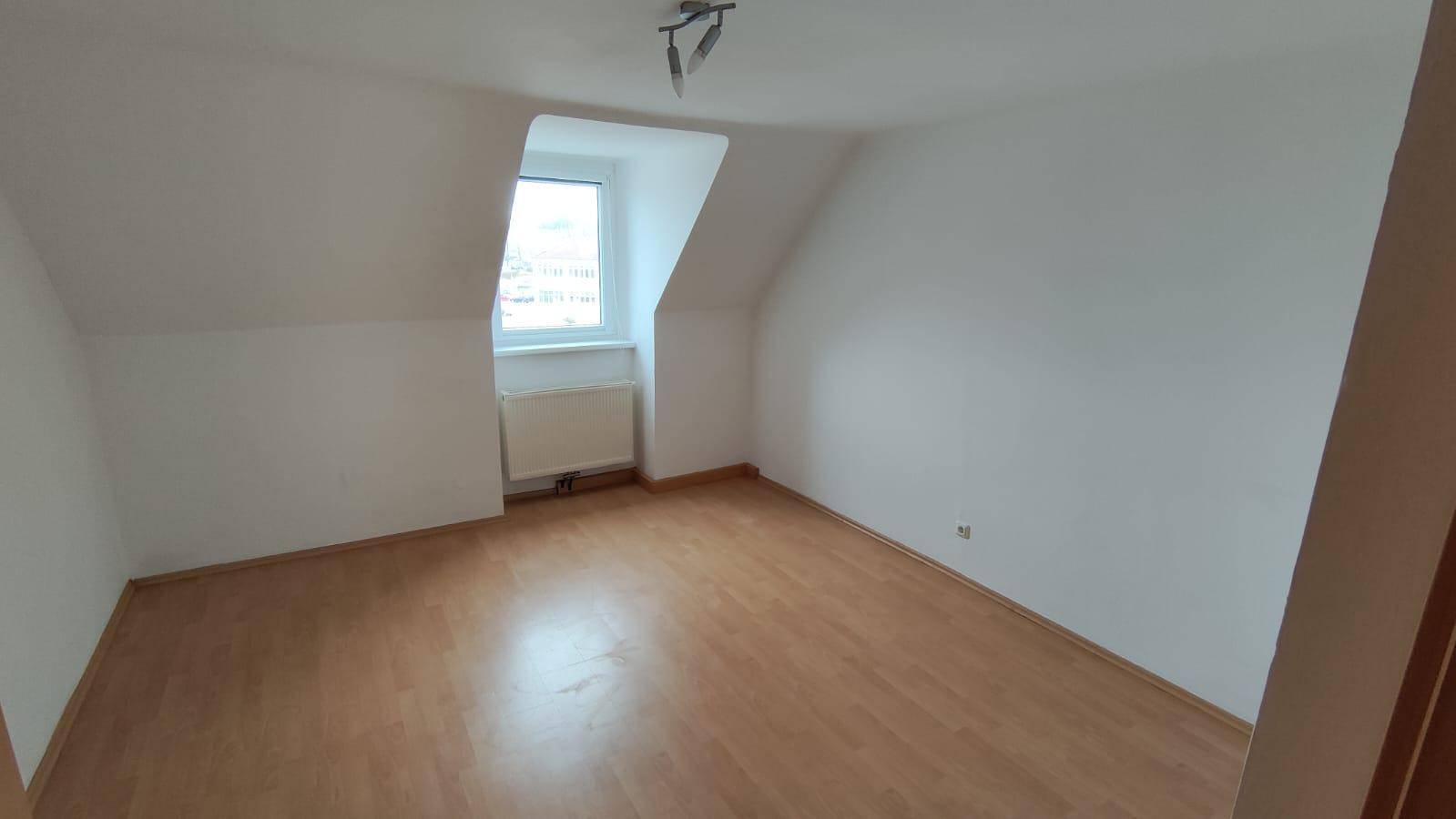 Helles Schlafzimmer im Dachgeschoss mit schräger Wand und Laminatboden.