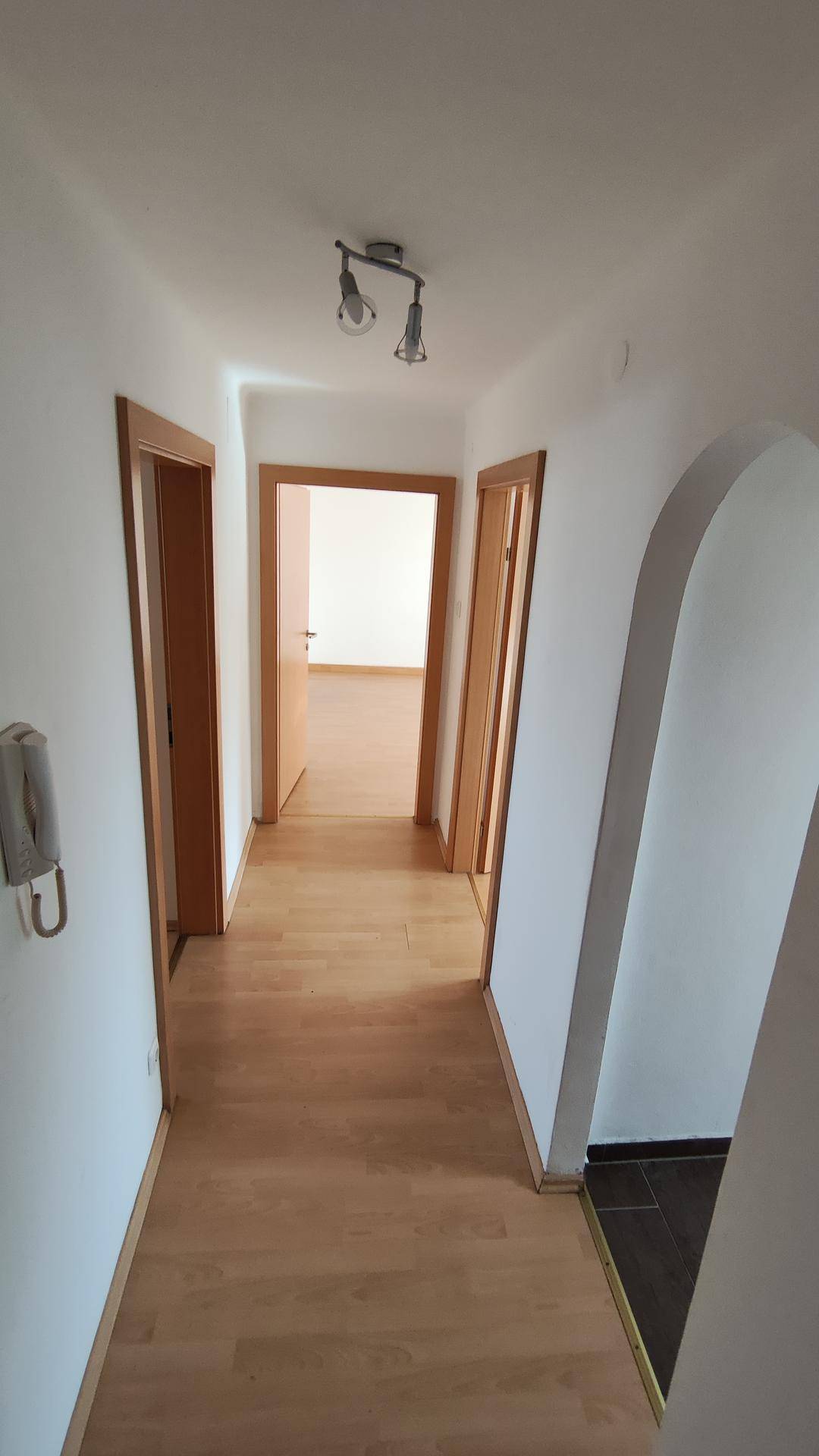 Heller Flur mit Laminatboden und mehreren Türen, die zu den Zimmern führen.