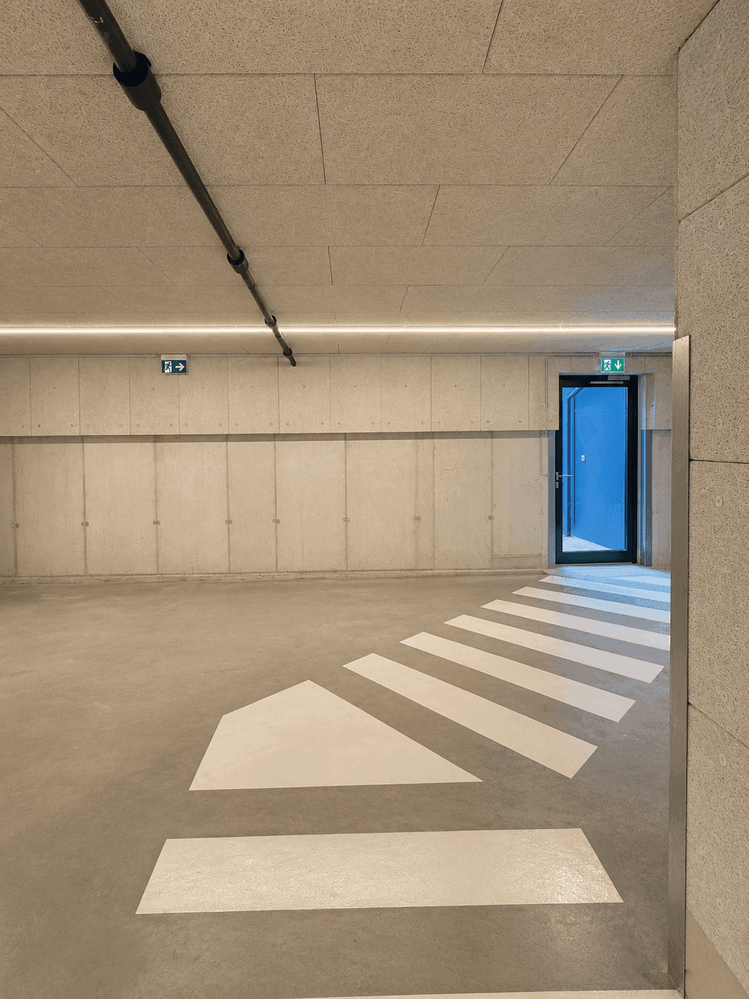 Ausgang einer Tiefgarage mit Fußgängerüberweg und moderner Beleuchtung.