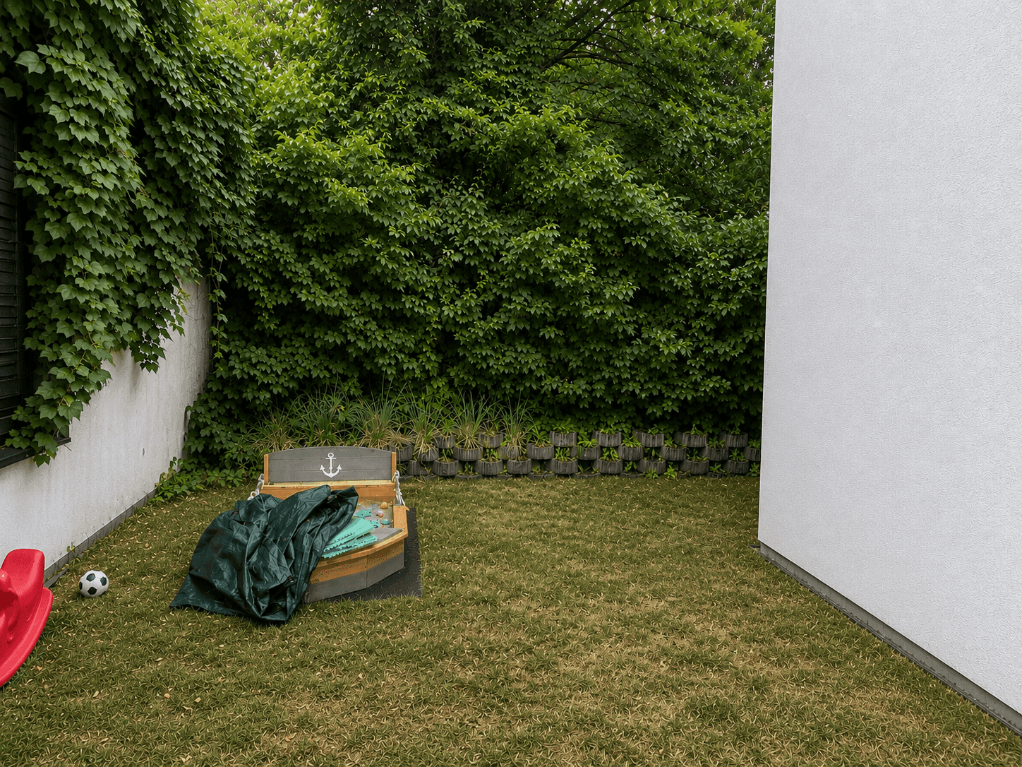 Gartenbereich mit Rasenfläche und einem kleinen Spielbereich in Bootsform.