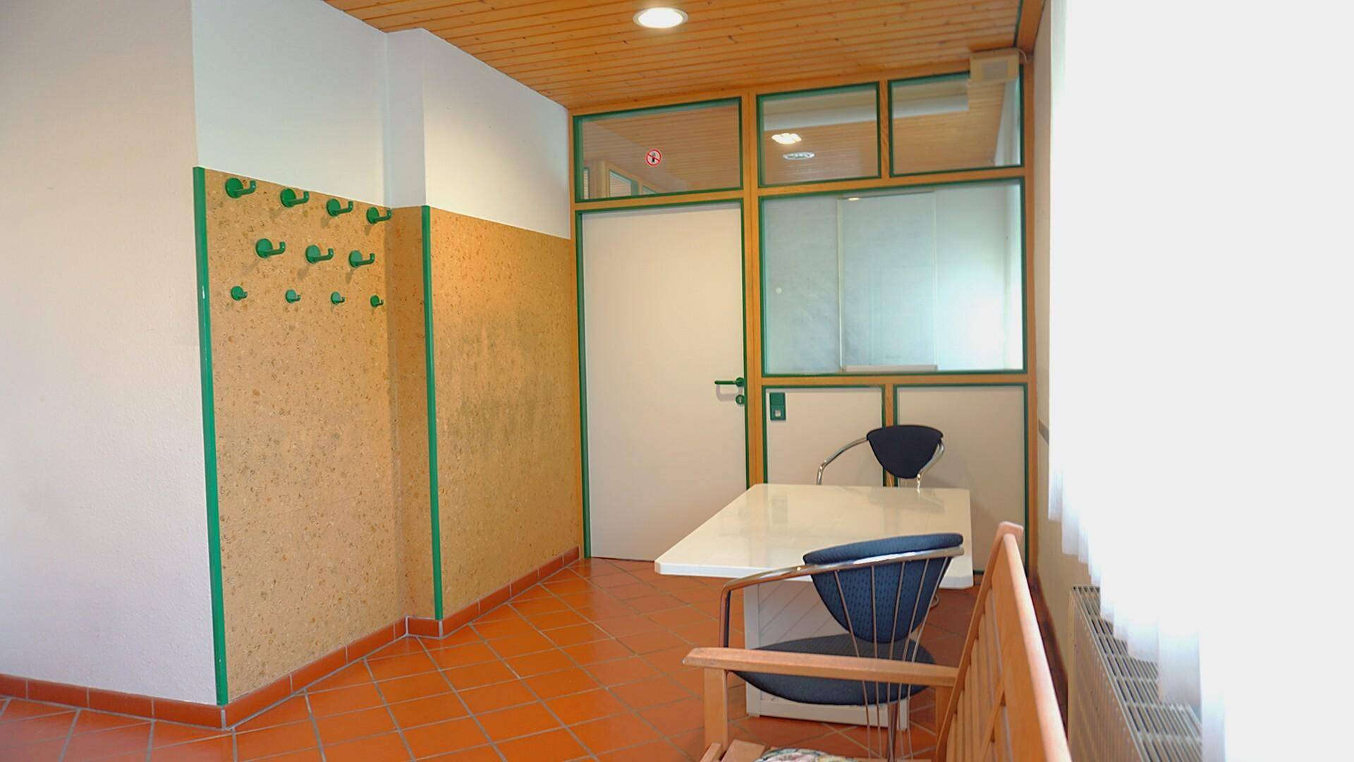 Funktionaler Raum mit Fliesenboden, Garderobe und Holzelementen.