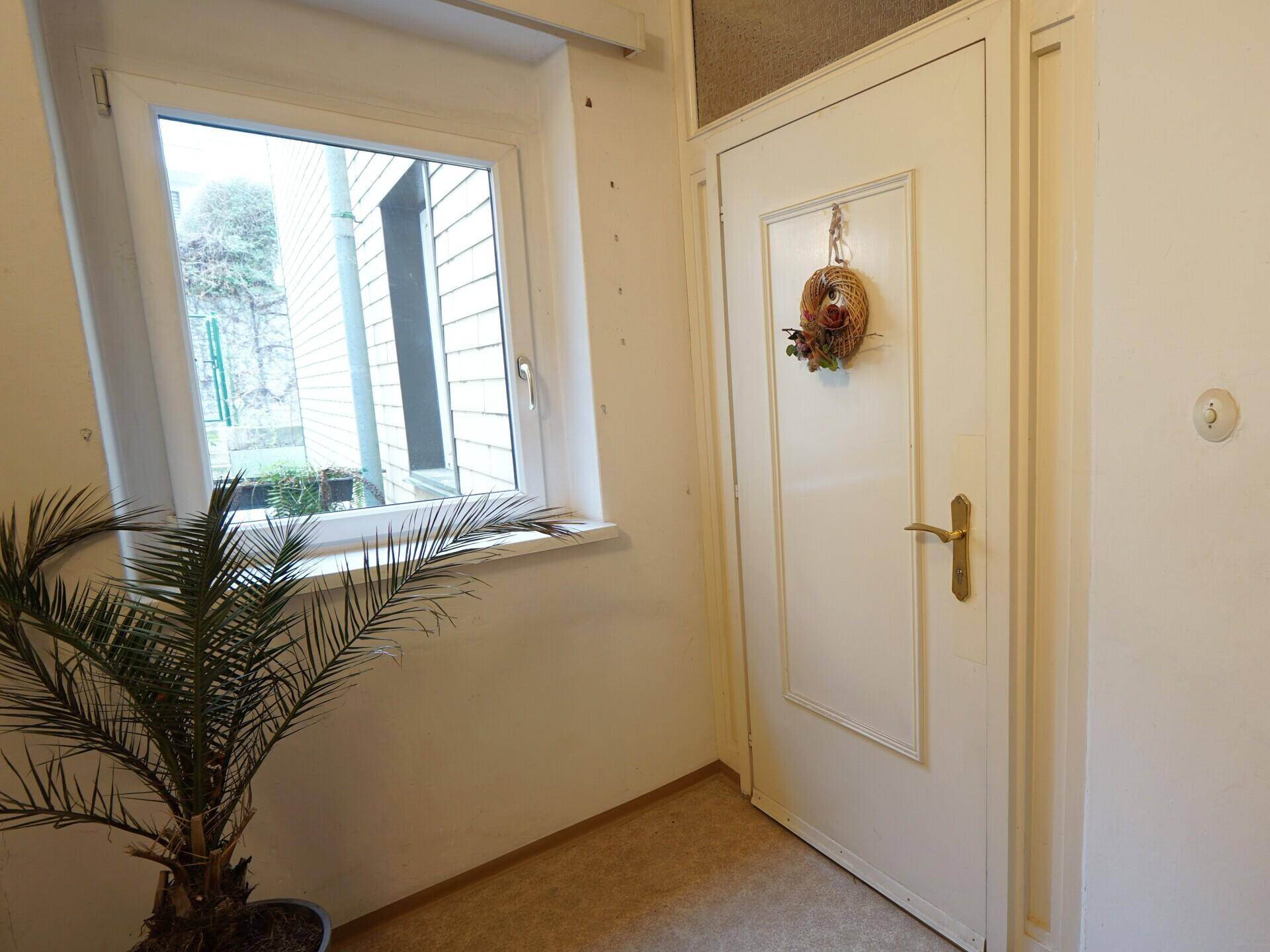 Heller Eingangsbereich mit Fenster und Haustür.